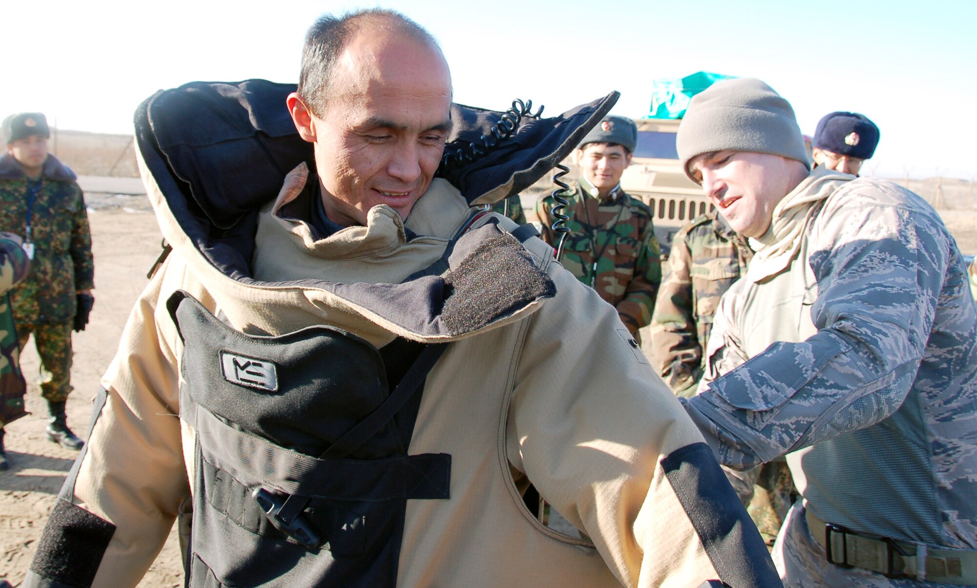 Tech. Sgt. Joseph Deslauriers assists Kyrgyz Lt. Col. Kadyrov Almazbek with putting on an explosive ordnance disposal protection suit Dec. 15, 2009, during the Kyrgyz Ministry of Defense team's visit to learn about EOD operations from Airmen with the 376th Expeditionary Civil Engineer Squadron at the Transit Center at Manas, Kyrgyzstan. The five-day visit, which enabled the Kyrgyz team get a close-up look at various EOD equipment, was to help the host nation build its EOD team. Sergeant Deslauriers is an EOD technician with the 376th ECES. (U.S. Air Force photo/Staff Sgt. Olufemi Owolabi)