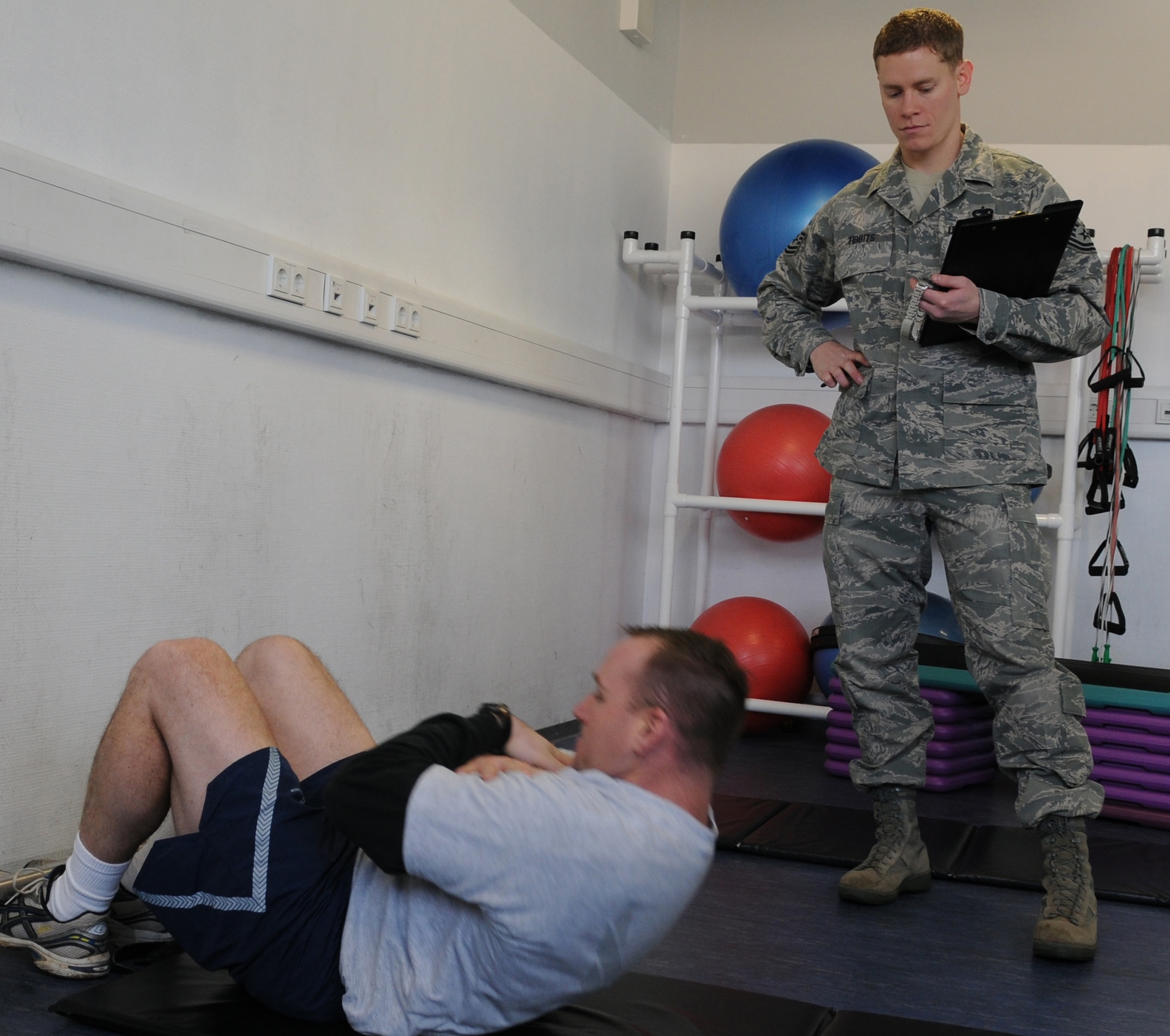 U.S. Air Force Tech Sgt. Aaron Tibbits times Tech. Sgt. Mark Malloy, both 1st Communications Maintenance Squadron special communications team members, during the sit-up portion of the AF physical training assessment, Ramstein Air Base, Germany, Dec. 16, 2009. Airmen across the Air Force are getting ready for the new pt standards. (U.S. Air Force photo by Airman 1st Class Alexandria Mosness)