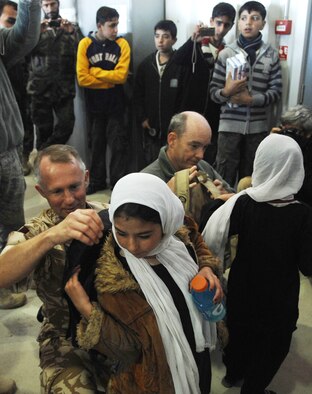 Air Commodore Malcolm Brecht, commander of Kandahar Airfield, assists a young girl with putting on a backpack filled with school supplies during her visit to Kandahar Airfield Dec. 31, 2009. (U.S. Air Force photo by Staff Sgt. Angelique N. Smythe/Released) 