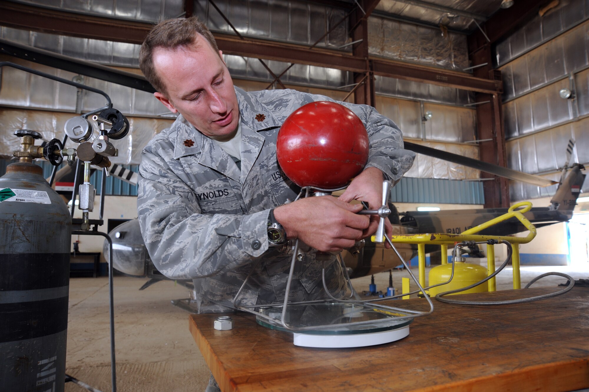 CAMP TAJI, Iraq -- Air Force Maj. William Reynolds, 721st Air Expeditionary Advisory Squadron maintenance operations officer demonstrates how to evacuate the liquid nitrogen from a fire suppression system bottle for the Mi-17 helicopter Dec. 27, 2009. Major Reynolds created a process that will save the Iraqi air force tens of thousands of dollars when approved. Major Reynolds is deployed from Luke Air Force Base, Ariz., and hails from Oakridge, Tenn. (U.S. Air Force photo/Master Sgt. Trish Bunting/Released)