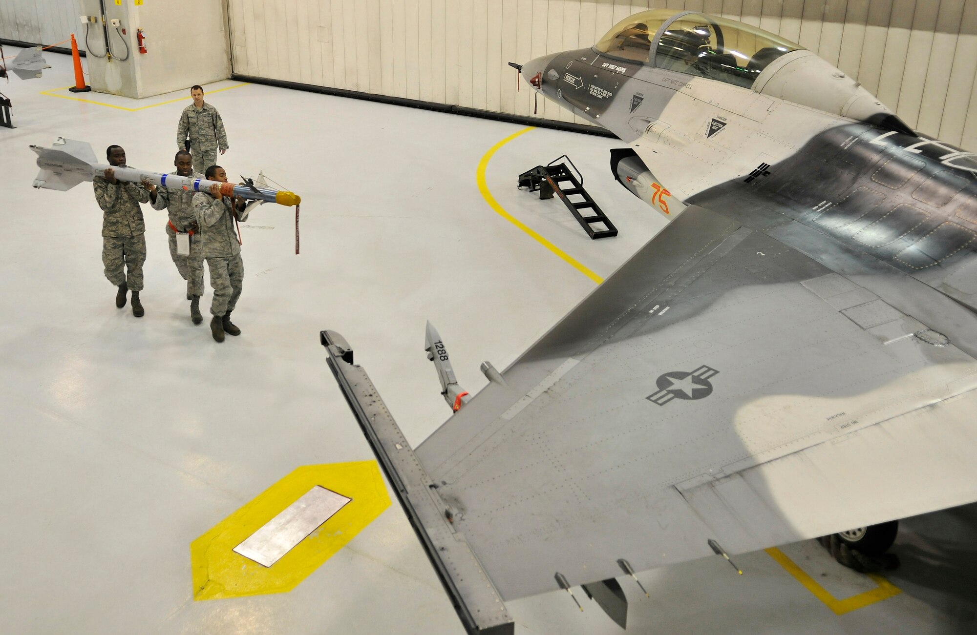 A weapons load crew team carries training munitions to an F-16 Fighting Falcon during the weapons load crew of the year competition Dec. 17, 2009, Eielson Air Force Base, Alaska. The load crew members are assigned to the 354th Aircraft Maintenance Squadron. (U.S. Air Force photo/Staff Sgt. Christopher Boitz)