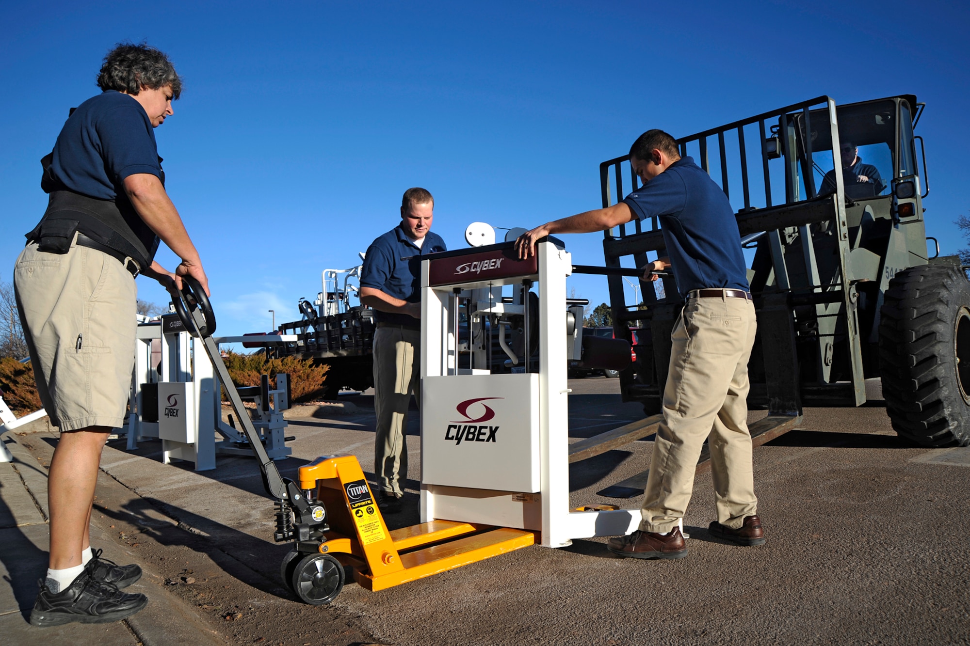 Monica Schwartz, Peterson Fitness and Sports Center operations director, Josh Fly, fitness specialist (center) and Senior Airman Antonio Jimenez, fitness specialist, move out old gym equipment Dec. 21 to make way for new weight and cardiovascular machines. The new equipment, which features MP3 docks, USB ports to record workouts, a wireless cardio theater, and virtual trainers is set up and ready to use. (Air Force photo by Craig Denton)