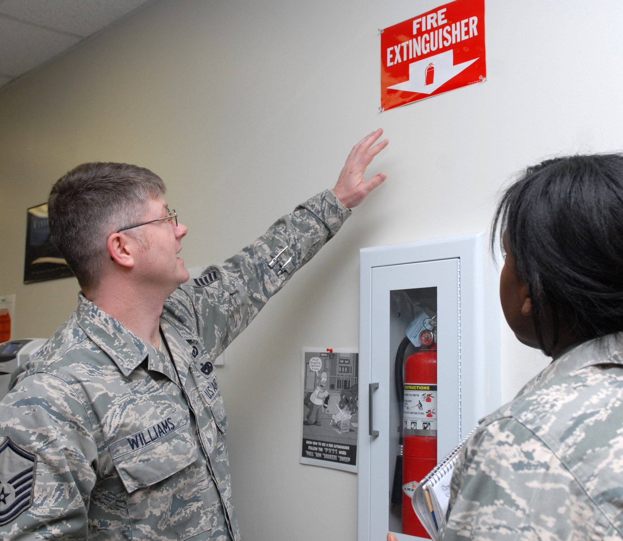 Master Sgt. Donald Williams, 19th Airlift Wing Safety ground safety superintendent, discussed fire extinguisher markings with Staff Sgt. Tamara Burks, 19th Comptroller Squadron budget analyst, during a safety inspection. (U.S. Air Force photo by Senior Airman Christine Clark)