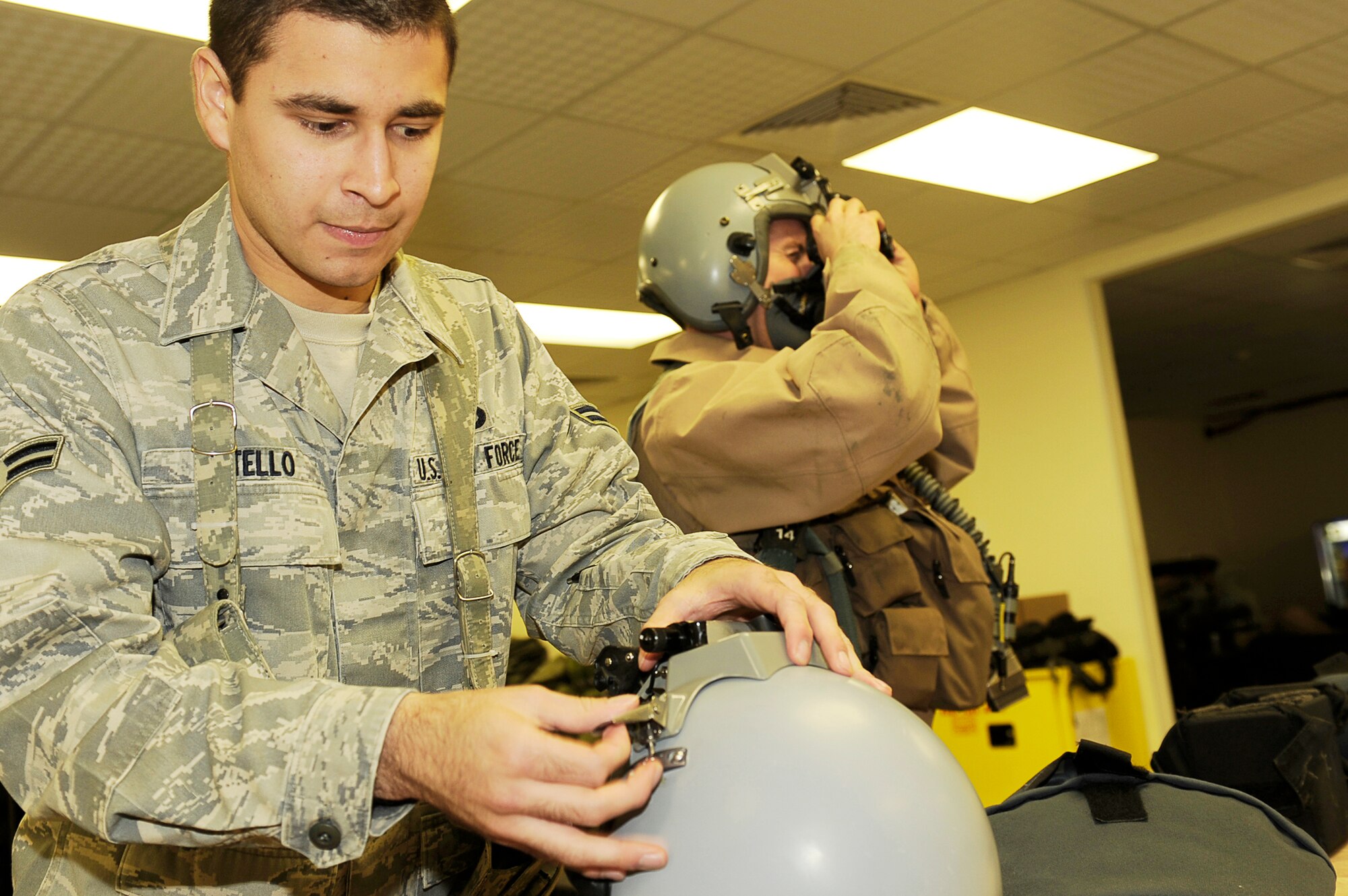Airman 1st Class Jeremy Betello works on a helmet while Capt. Austin Brown, 79th Expeditionary Fighter Squadron, prepares for his flight Jan. 4, 2010. Airman Betello is assigned to the Life Support section for the 455th Expeditionary Operation Support Squadron. Captain Brown is from Fountain Hills, Ariz. Both are stationed at Shaw Air Force Base, S.C. (U.S. Air Force photo/Tech. Sgt. Jeromy K. Cross)