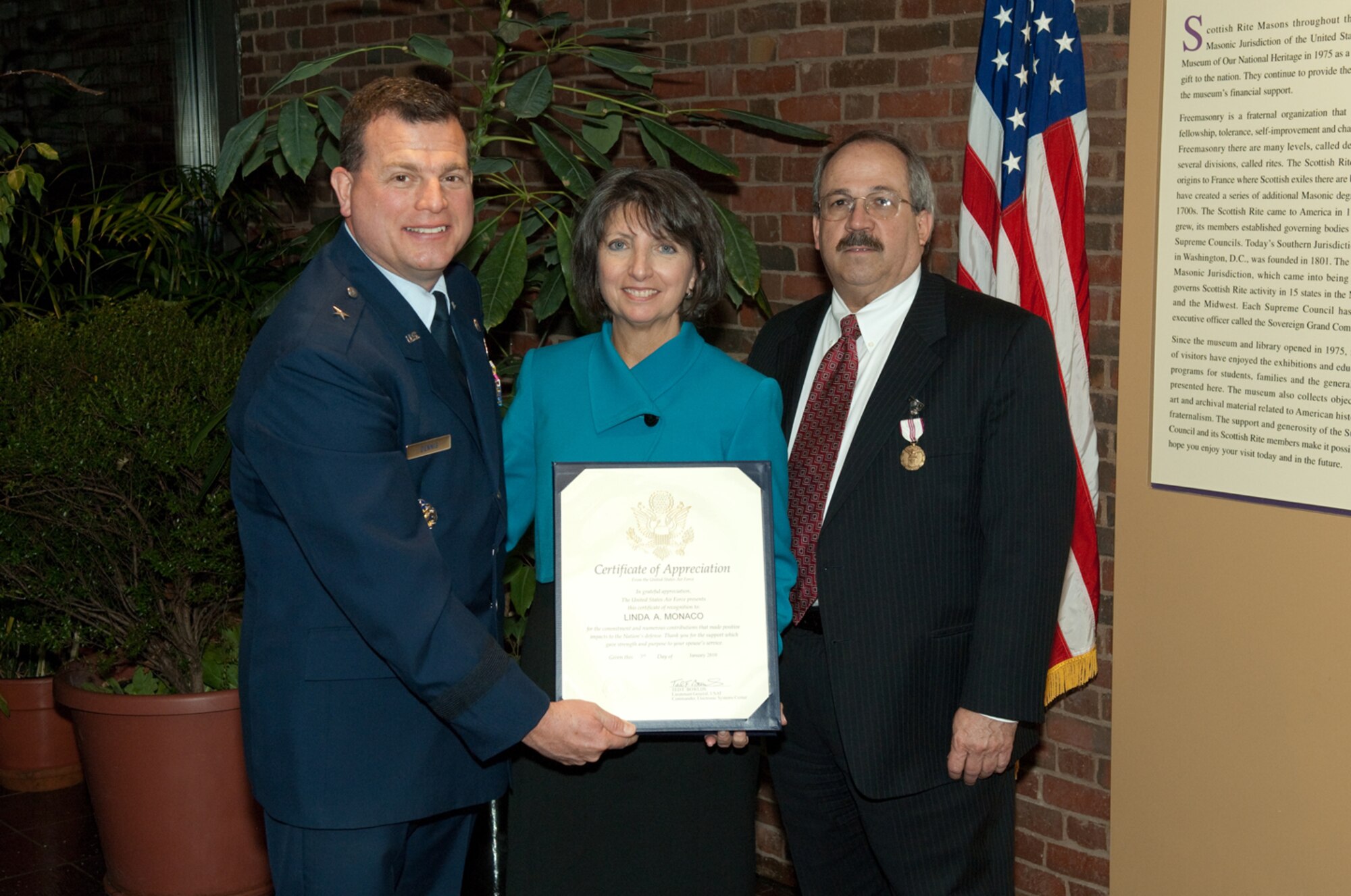 Former 551st Electronic Systems Wing Commander Brig. Gen. Dwyer L. Dennis, now director of Intelligence and Requirements at Air Force Materiel Command, presents a Certificate of Appreciation to Linda Monaco during her husband's retirement ceremony Dec. 30. Anthony Monaco, who had been serving as 551 ELSW deputy director, retired Jan. 3, after more than 30 years of federal service at Hanscom AFB. (USAF photo by Rick Berry.)