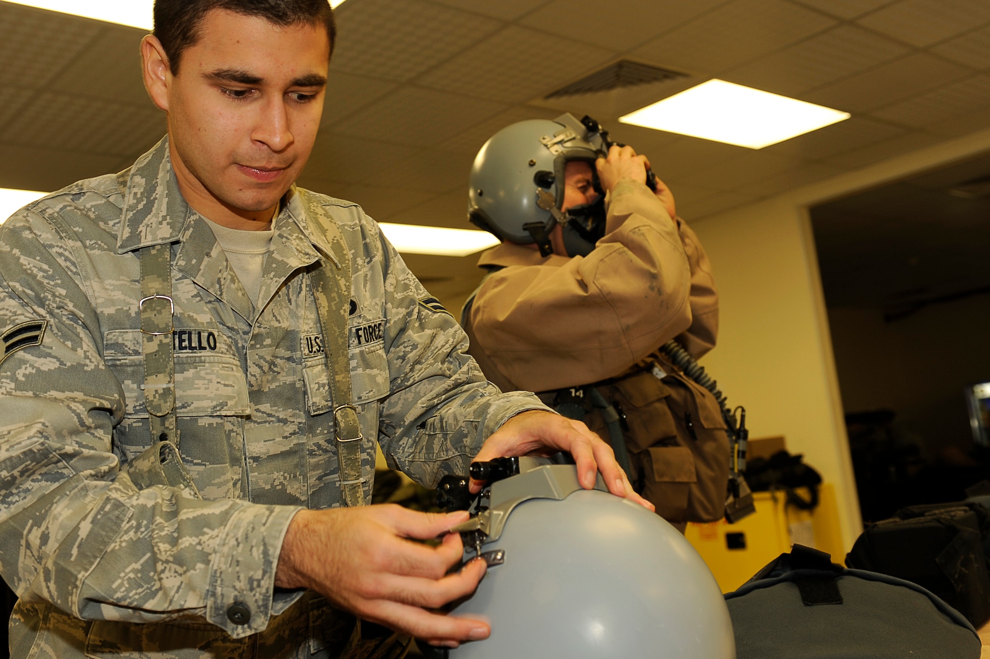 BAGRAM AIRFIELD, Afghanistan--U.S. Air Force Airman 1st Class Jeremy Botello, aircrew flight equipment specialist, 455th Expeditionary Operations Support Squadron, works on a helmet while Capt. Austin Brown, 79th Expeditionary Fighter Squadron, prepares for his flight Jan. 4, 2010.  Airman Betello is from Austin, Texas, and Brown is from Fountain Hills, Ariz. Both are stationed at Shaw Air Force Base, S.C. (U.S. Air Force photo by: Tech. Sgt. Jeromy K. Cross)