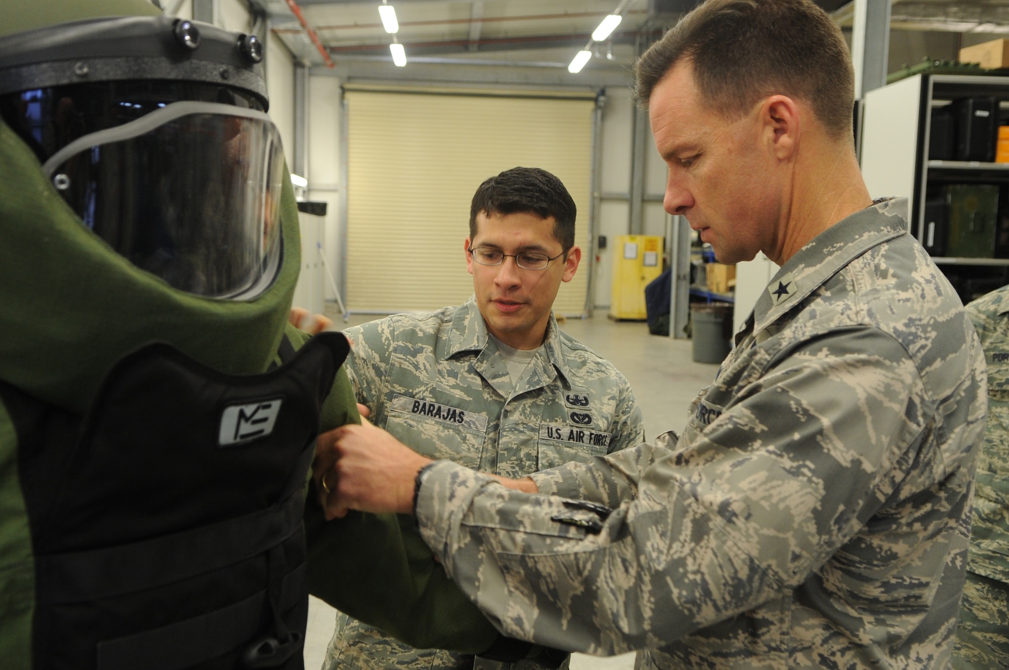 Airman 1st Class Michael Poffenberger poses in an EOD-9 bombsuit while Brig. Gen. Mark C. Dillon, 86th Airlift Wing commander, receives a brief overview on the suit's construction and functionality from A1C Christopher Barajas, 886 Civil Engineer Squadron while visiting the Explosive Ordinance Disposal facility on Ramstein Air Base Germany on December 12, 2009. (U.S. Air Force photo by Tech. Sgt. Sean M. White)