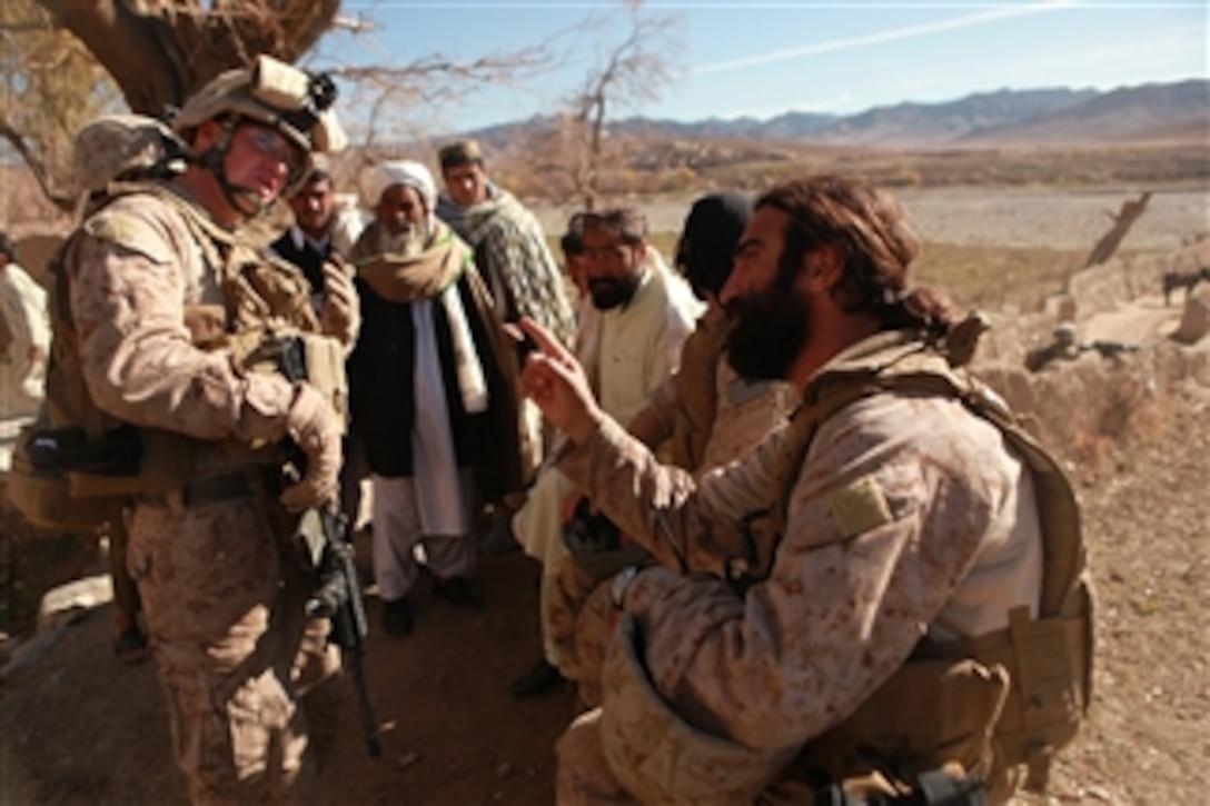 U.S. Marine Corps 1st Lt. Patrick Kelly (left) with India Company, 3rd Battalion, 4th Marine Regiment uses an interpreter to speak with Afghan men during a patrol through the village of Sahtut, Afghanistan, on Dec. 25, 2009.  