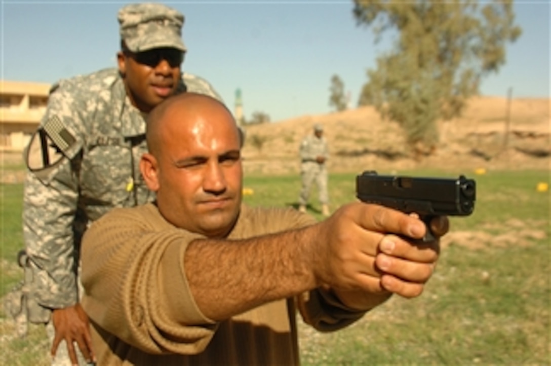 U.S. Army Sgt. 1st Class Thomas Reese, assigned to the Border Transition Team 4130th, helps train Iraq border guards in basic pistol drills at the west gate of the Muntheria Port of Entry along the Iraq/Iran border in Diyala, Iraq, on Dec. 15, 2009.  