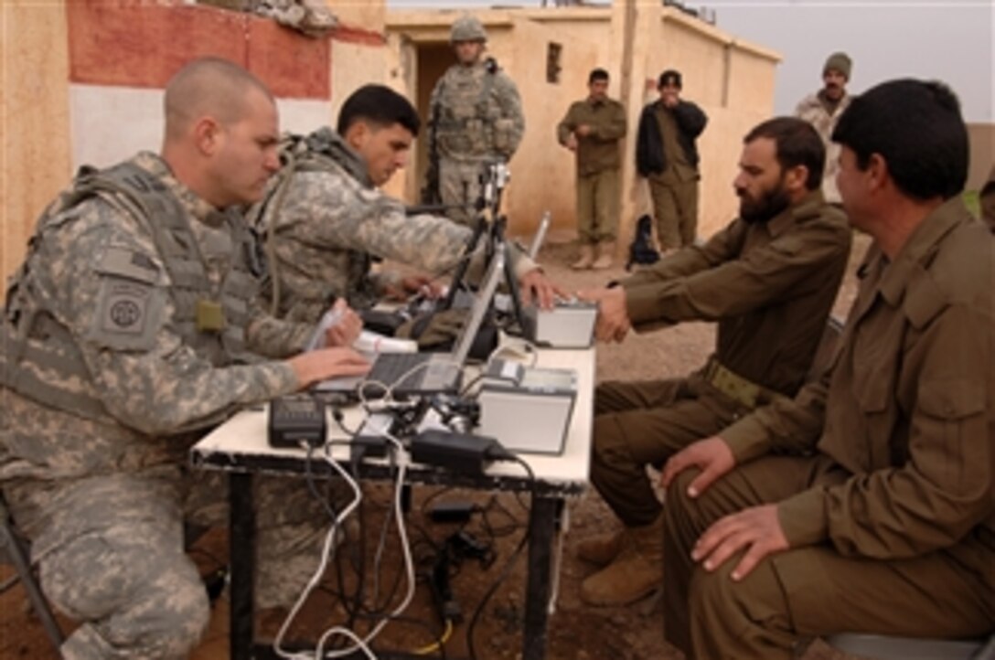 U.S. Army Spc. Patric Flinn and Sgt. Andres Rivera, both assigned to 3rd Squadron, 73rd Cavalry Regiment, 1st Brigade, 82nd Airborne Division, work to store information on Iraqi border patrol members serving near the Syrian border in western Iraq on Jan. 3, 2010.  