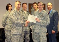 MINOT AIR FORCE BASE, N.D. -- Capt. James Olson of the 91st Maintenance Operations Squadron receives an award for best decorated house of the holiday lights contest from Col. James Gallagher, 5th Mission Support Group commander, Small tokens like these show Minot's continued effort to increase base morale through the cold winter months. (Courtesy photo)