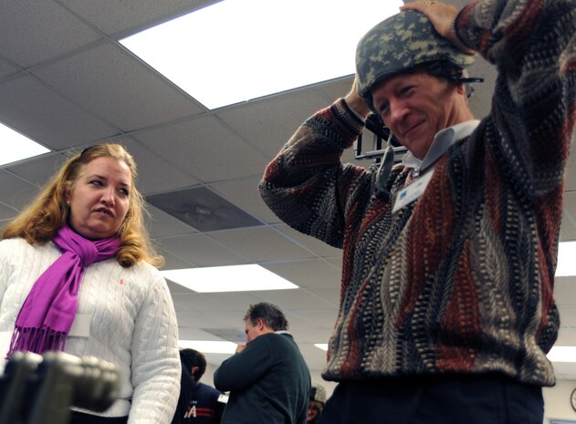 Jim Geffert tries on a protective helmet as Cheryl Clark watches during the honorary commanders induction held here Jan. 5. During the induction, honorary commanders had the opportunity to experience the Expeditionary Combat Skills Training Airmen are required to complete prior to deployments. Mr. Geffert is the honorary commander assigned to the 437th Airlift Wing vice commander and Ms. Clark is the honorary commander assigned to the 437 AW commander. (U.S. Air Force photo/Senior Airman Katie Gieratz)(RELEASED)