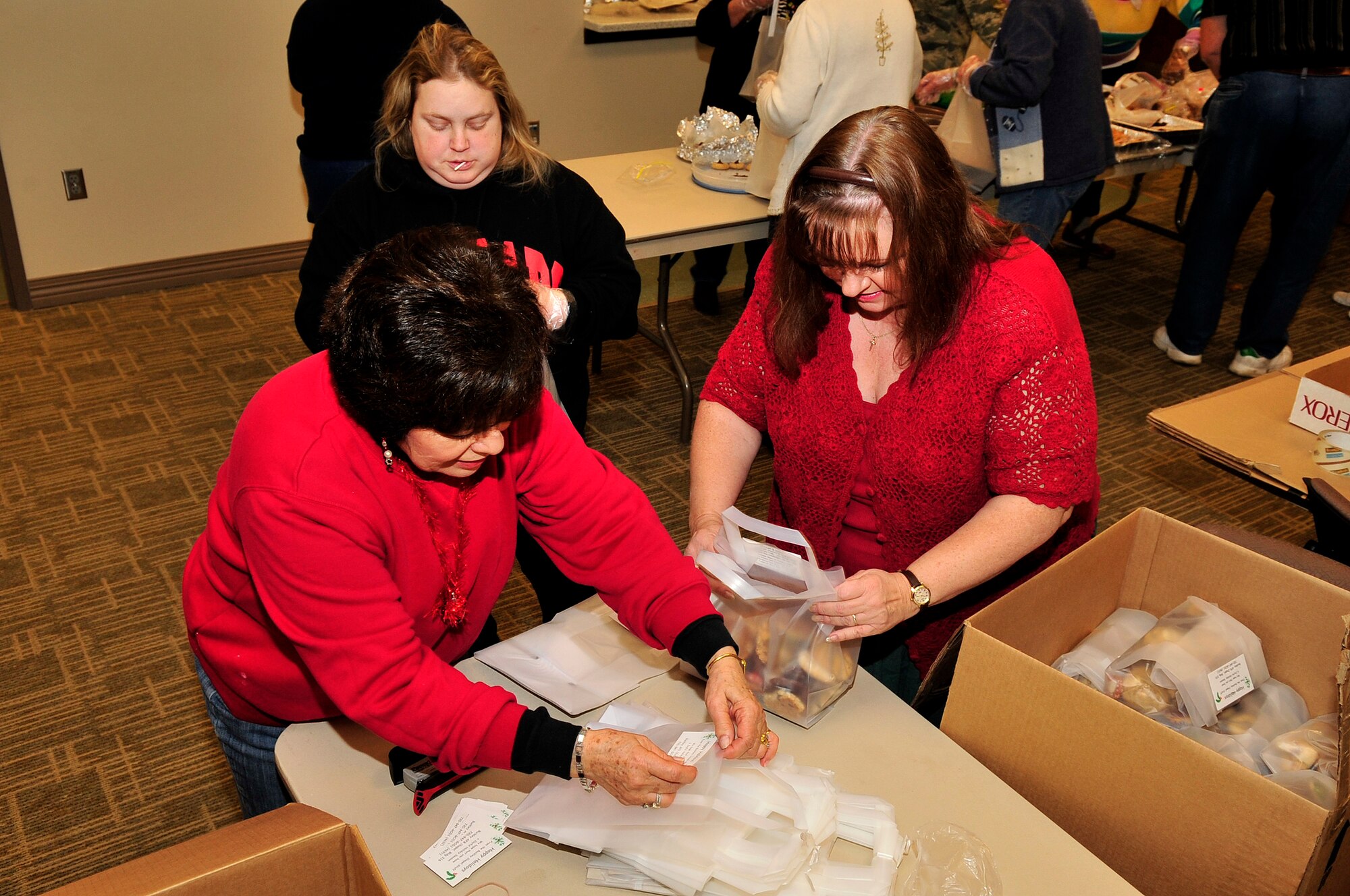 BUCKLEY AIR FORCE BASE, Colo. -- Flo Vennen, Penny Sutton and Debbie Cruz help prepare the finished bags from the cookie caper for delivery at the base chapel Dec. 15, 2009. 154 dozen bags were delivered around the base and to dorm residents. (U.S. Air Force Photo by Airman 1st Class Manisha Vasquez)