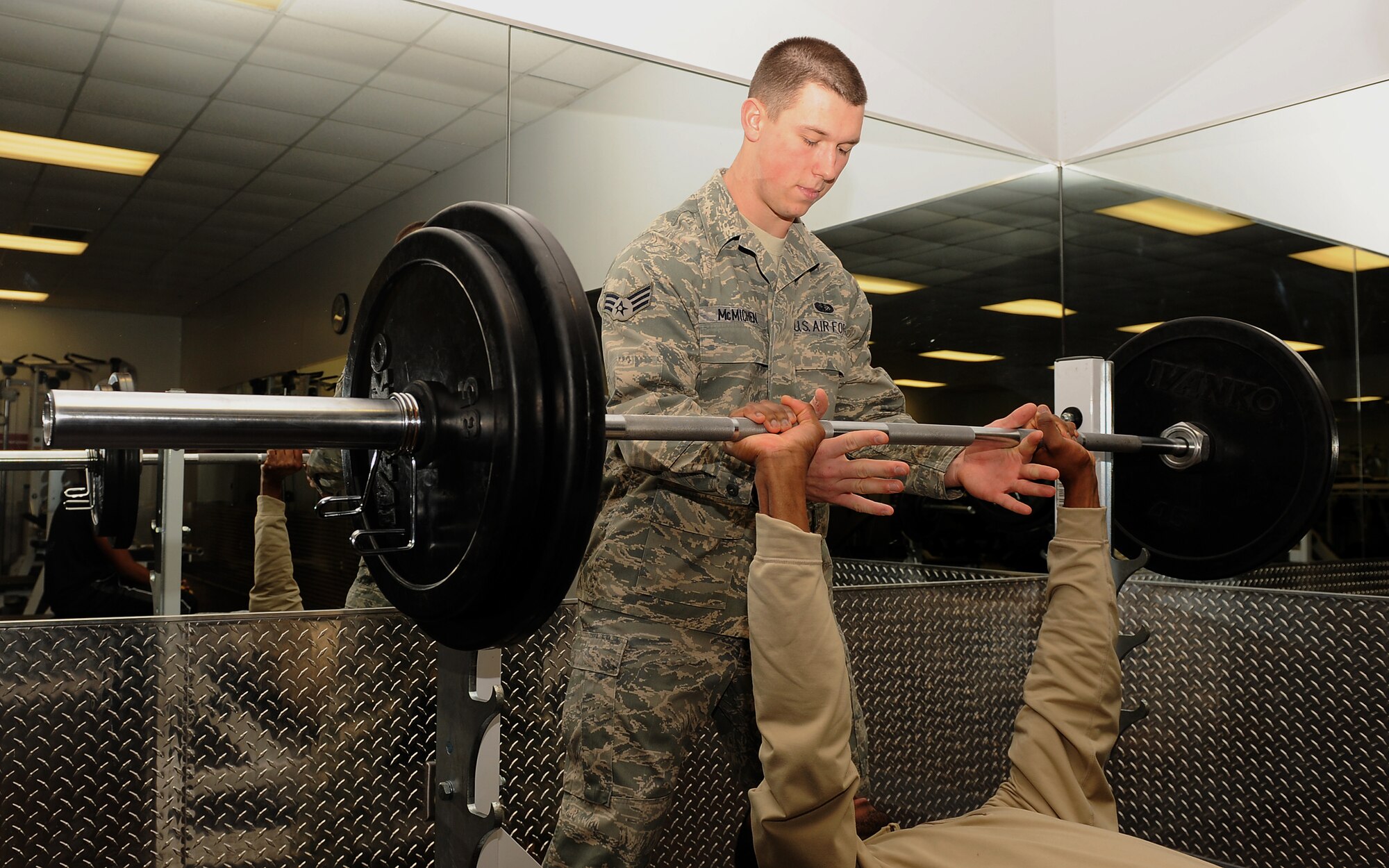 Senior Airman Adam McMichen, spots Airman 1st Class Trymond Rubin on Seymour Johnson Air Force Base, N.C., Jan. 4, 2010. Both Airmen are 4th Force Support Squadron fitness and sports specialist. Members of the fitness center staff can assist people during a workout as a spotter. Spotting another Airman follows the wingman concept and helps people maintain the correct form when doing exercises and helps prevent injuries by supporting heavy weights. (U.S. Air Force photo/Senior Airman Whitney Lambert)
