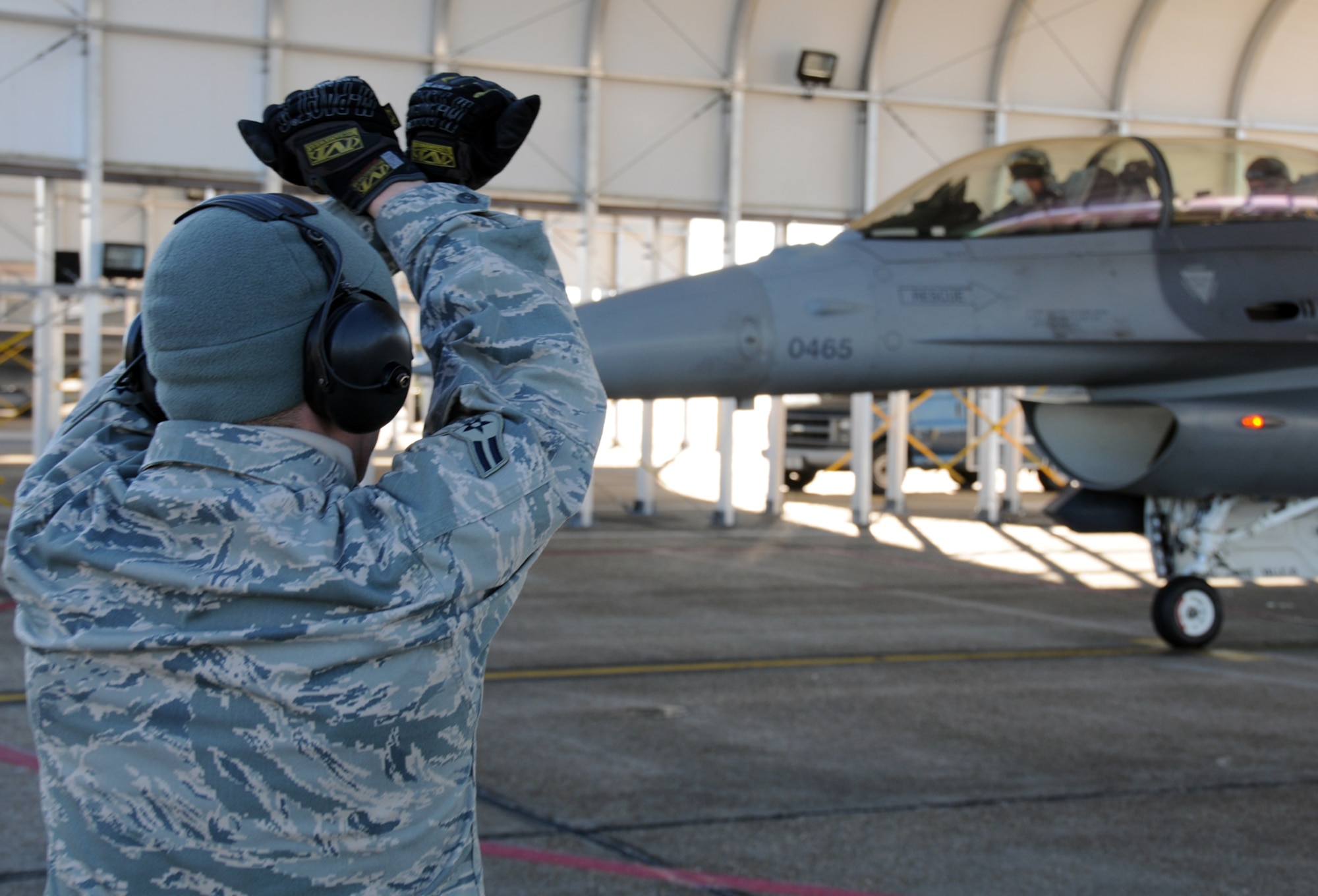 EGLIN AIR FORCE BASE, Fla. -- Airman 1st Class Travis Young, 46th Aircraft Maintenance Squadron, signals an F-16 off as it taxis to the runway. Northwest Florida was hit by a massive cold front sending temperatures plummeting well below freezing. Despite the cold, the maintainers must prepare the jets and get them in the air. (U.S. Air Force photo/Airman 1st Class Anthony Jennings)