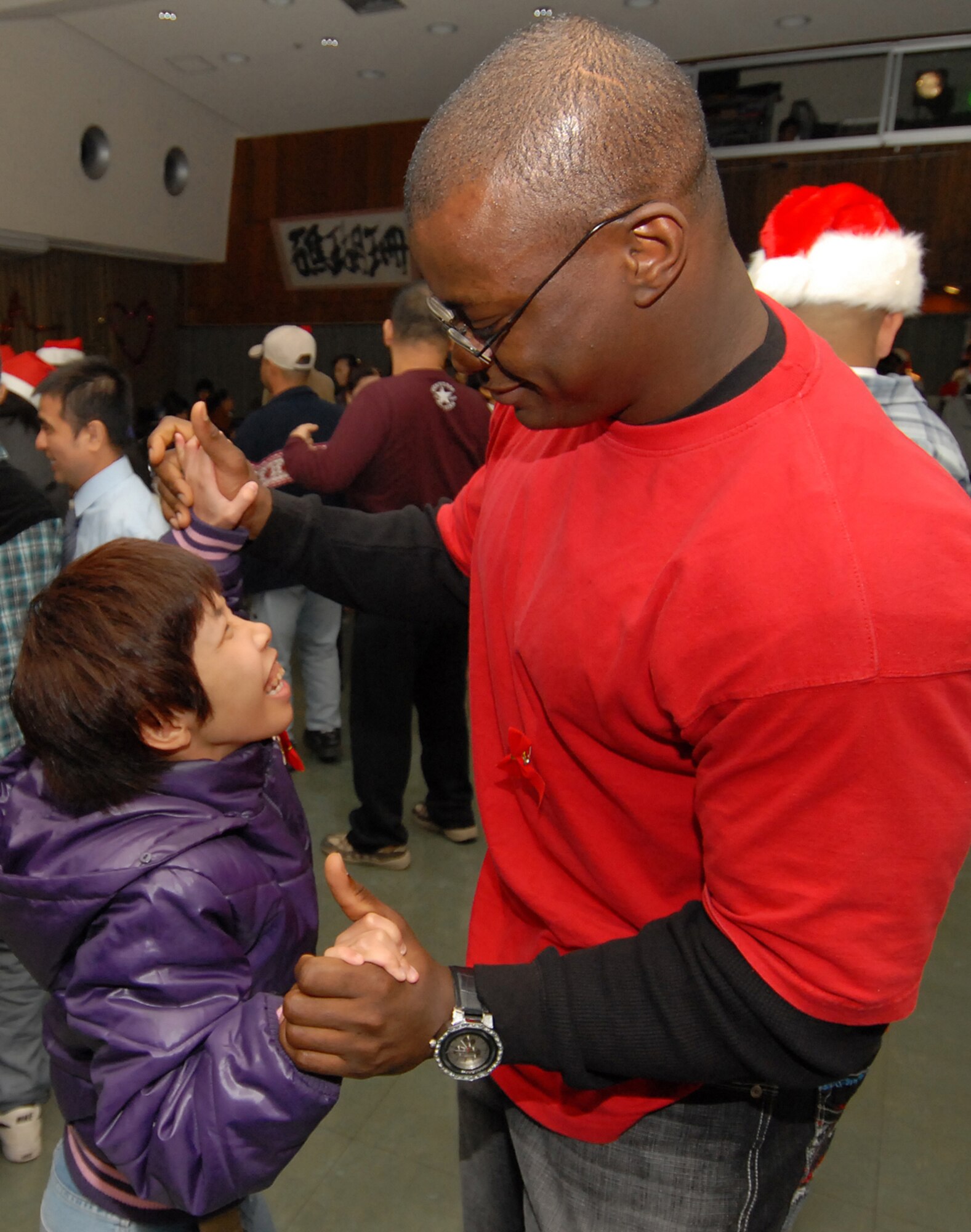 Staff Sgt. Adeyemo Adegboyega, 18th Civil Engineer Squadron, dances with a child during a holiday party at the Yomitan Social Welfare Center Dec. 19. Half a dozen volunteers representing Kadena handed out more than 150 gifts, several holiday cakes and clothing donations for families of special needs children and adults. (Air Force/Staff Sgt. Jason Lake)