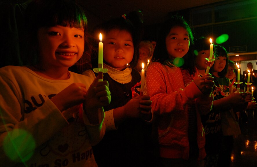 Okinawan children hold out their friendship candles as members of the Yomitan Social Welfare Center celebrate Christmas with half a dozen Kadena volunteers Dec. 19. Volunteers from the 18th Civil Engineer Squadron and 18th Communications Squadron represented Kadena Air Base and handed out more than 150 gifts, several holiday cakes and clothing donations to families of special needs children and adults. (Air Force/Staff Sgt. Jason Lake)