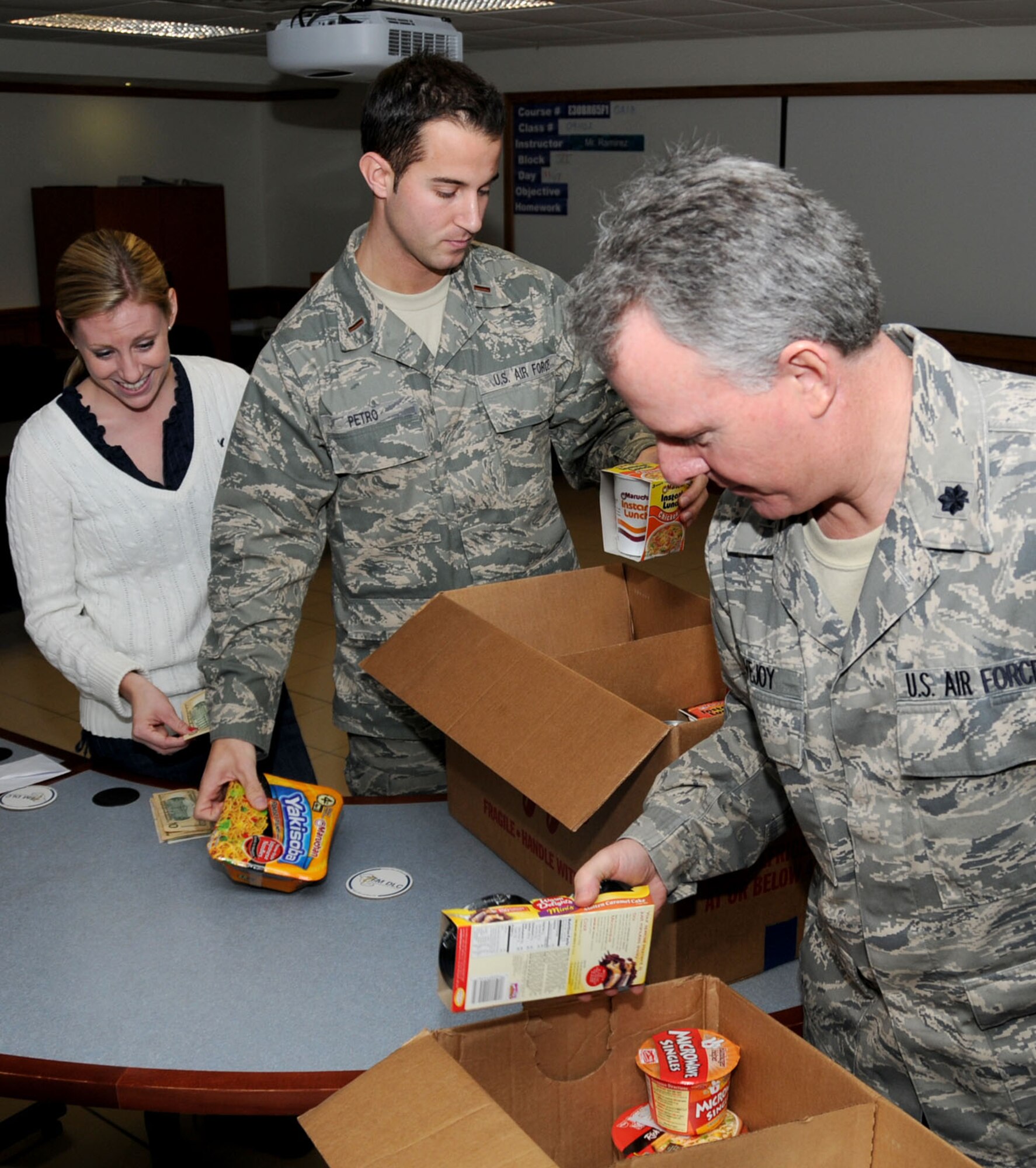 From left, Mallory Freund, 2nd Lt. Jake Petro and Lt. Col. Ben Lovejoy, students in the 335th Training Squadron’s basic financial managment officer course, box up food collected for the Bay Area Food Bank.  The class contributed 79 pounds of food and $492 to the organization.  (U.S. Air Force photo by Kemberly Groue)