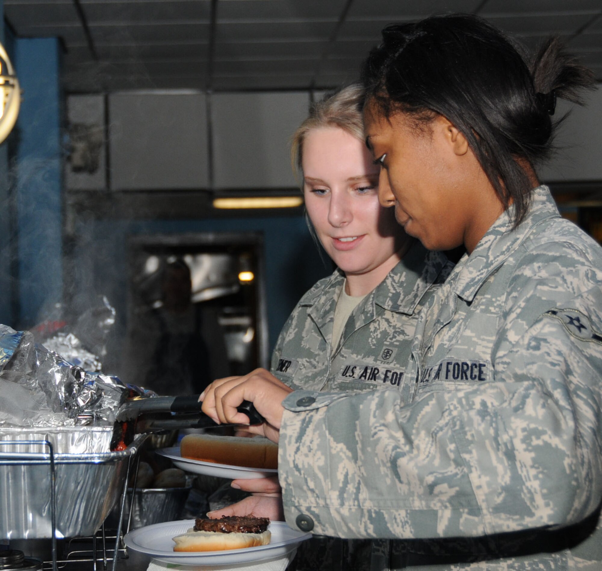 Airmen Tasha Doerner and Cristina Aguilar, 81st Dental Squadron, who are each other’s wingman, help themselves to dinner at the burger burn.   (U.S. Air Force photo by Kemberly Groue)