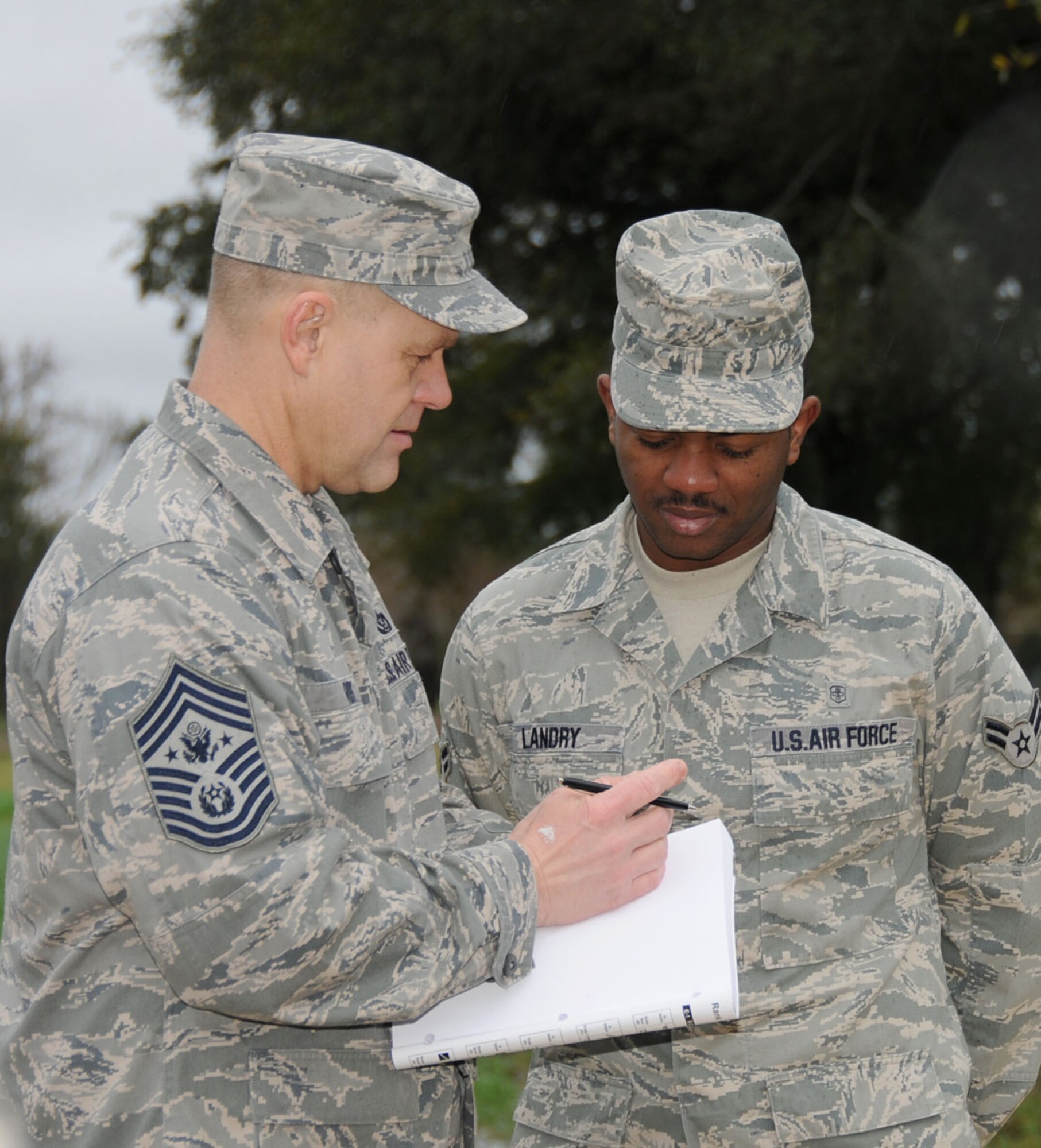 Chief Roy signs a handbook for Airman 1st Class Mark Landry, 81st Aerospace Medicine Squadron, following a Dec. 18 groundbreaking for the first of up to four new permanent party dormitories.  Airman Landry represented current dorm residents at the ceremony.  (U.S. Air Force photo by Kemberly Groue)