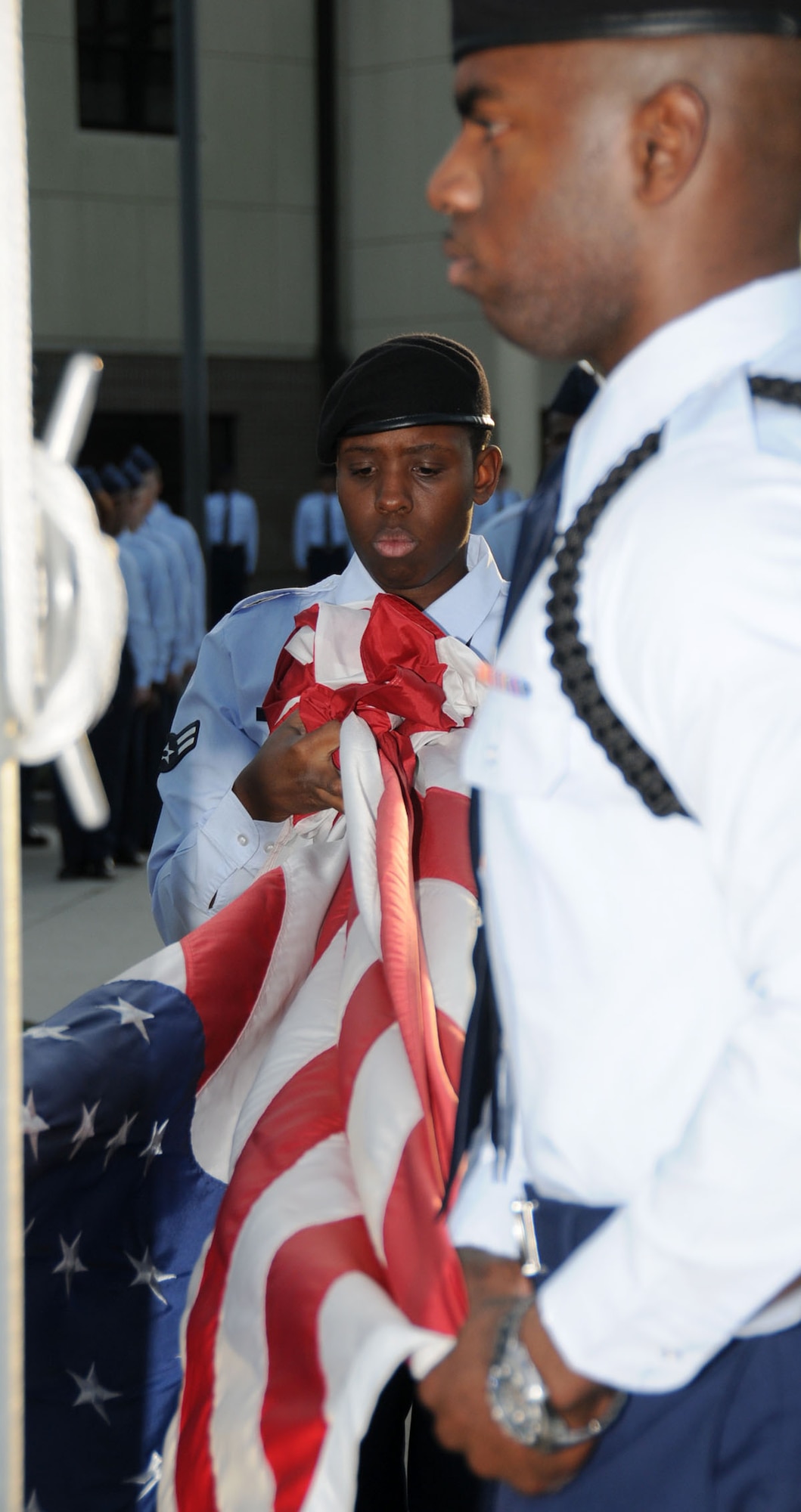 Airman 1st Class Amber Pate, left, straightens the flag before folding along with Airman Basic Michael Ford as students from the 338th Training Squadron conduct the base’s final formal retreat ceremony for 2009 on Dec. 16 in front of the Levitow Training Support Facility.  The student exodus began Dec. 19, and trainees reported back to Keesler Saturday.  (U.S. Air Force photo by Kemberly Groue)