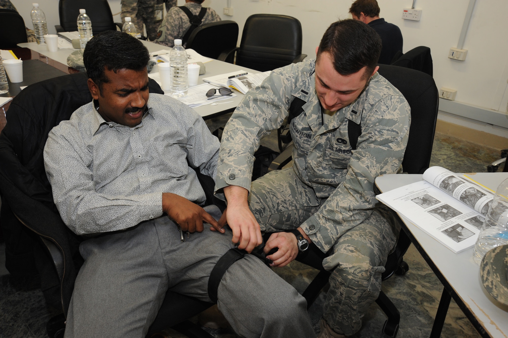 1st Lt. Micah Bowron practices applying a tourniquet on Sankar Shunmugasundaram during a combat lifesaver training course Dec. 29, 2009, at Baghdad, Iraq. Lieutenant Bowron is a heavy equipment procurement officer for U.S. Forces-Iraq, Deputy Commanding General-Advising and Training Health Affairs. Mr. Shunmugasundarama is a dining facility quality assurance and quality control manager for Almco. (U.S. Air Force photo/Master Sgt. Trish Bunting)