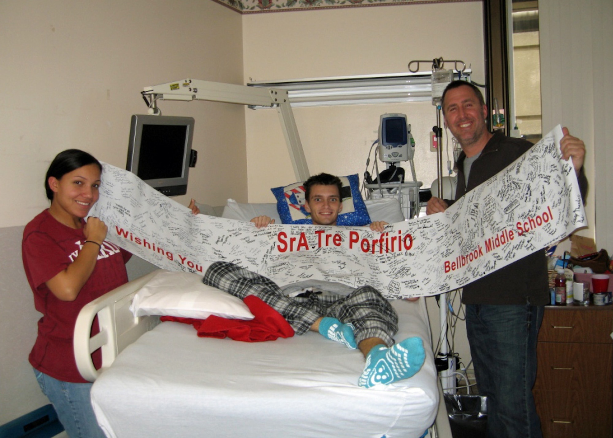 Senior Airman Tre Porfirio (center), Airman First Class Ahja Nock, and Lt.
Col. Rick Johns, hold a banner of get well wishes from Bellbrook (Ohio)
Middle School students Dec. 29, 2009 at Walter Reed Army Medical Center.  Porfirio is recovering after a groundbreaking Thanksgiving Day surgery when doctors
removed his damaged pancreas, harvested islet cells and transplanted them
into his liver.  A communications technician with the 88th Communications Squadron, Senior Airman Porfirio was shot in the back by an insurgent while
deployed with an Army unit to Afghanistan.  Nock is a mental health technician with the 88th Medical Operations Squadron and Johns is commander of the 88th
Communications Squadron.  All three Airmen are assigned to Wright-Patterson
Air Force Base, Ohio. (courtesy photo)
