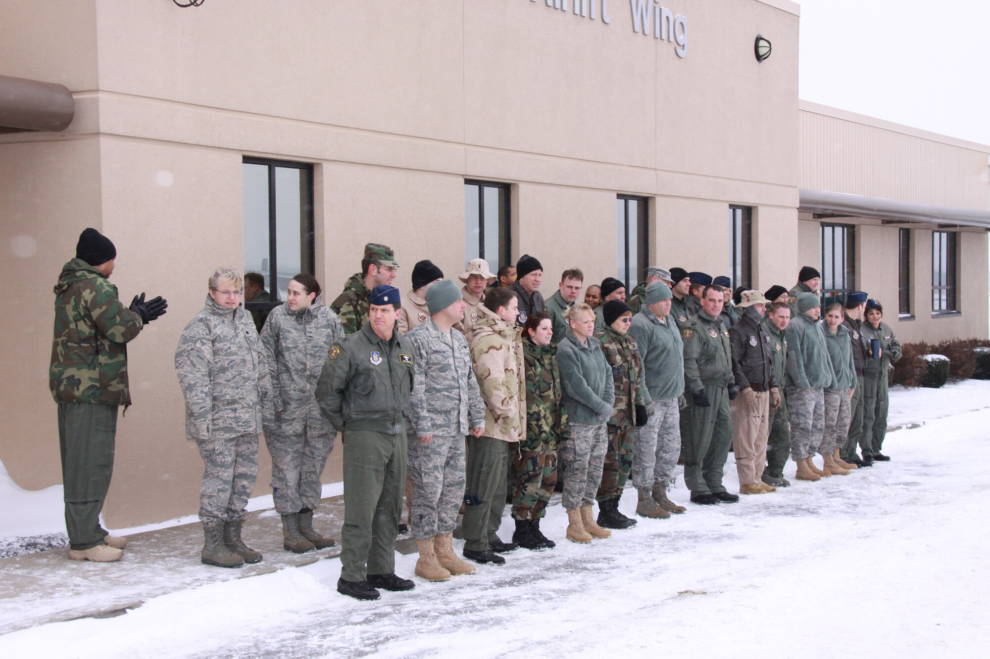 Members of the 911th Airlift Wing's Operation Group wait in the frigid cold, Jan. 6, 2010 in order to wave goodbye to the taxiing C-130 Hercules carrying their comrades. Those aboard the aircraft, operations and maintenance personnel, deploy for approximately four-month's in support of Overseas Contingency Operations.