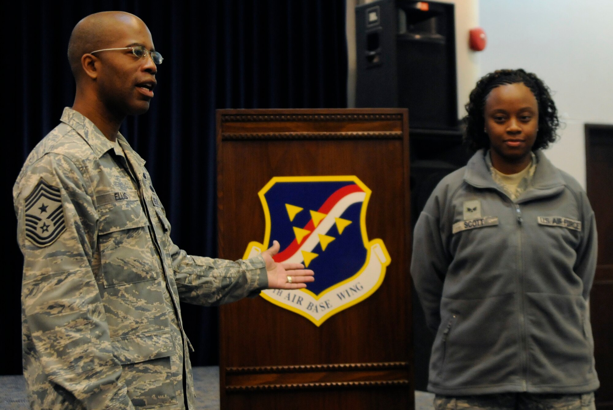 Chief Master Sgt. Robert Ellis, 39th Air Base Wing command chief, uses Senior Airman Queen-ella Scott as an example for the new sage green fleece Wednesday, Jan. 6, 2010 during the first commander’s call of the New Year. Chief Ellis highlighted the commander’s topics about the updated standards for physical training tests and Air Force uniforms for 2010. (U.S. Air Force photo/Airman 1st Class Amber Ashcraft)