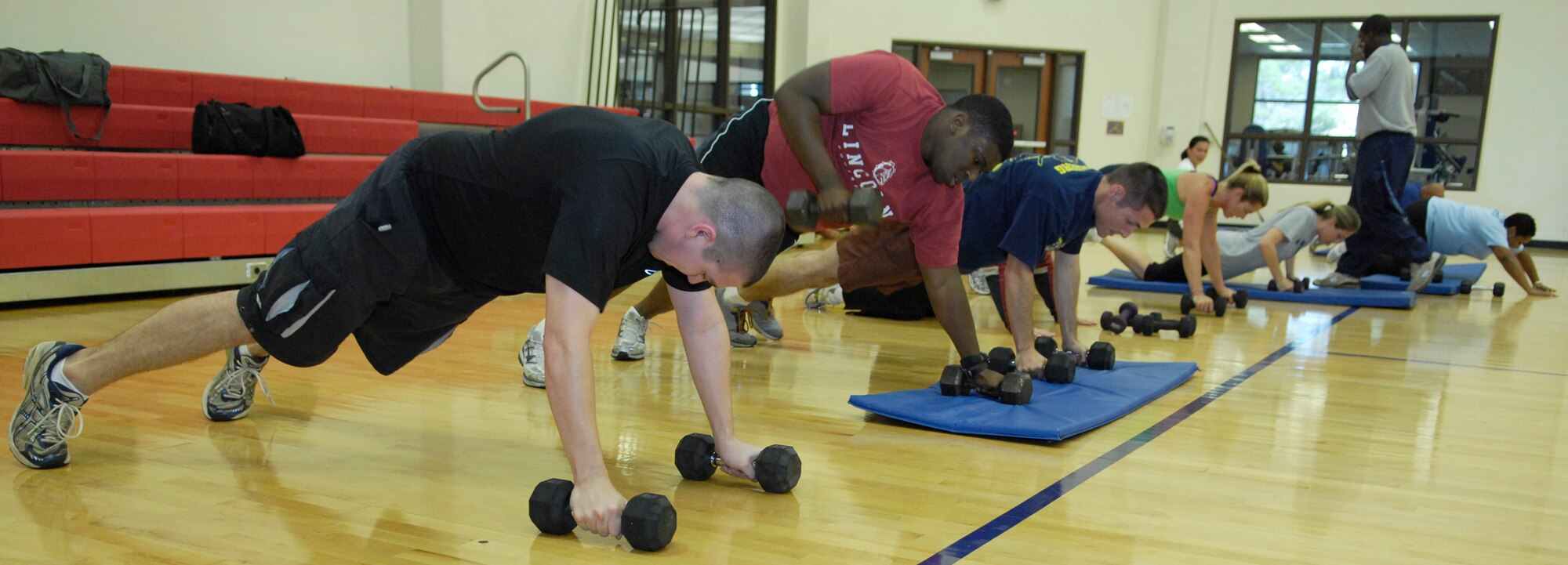 VANDENBERG AIR FORCE BASE, Calif. - Sweating off calories, a group of attendees at the Hardcore 30-Minute Workout, do push-up rolls with weights here Wednesday, Jan. 6, 2010. The workout program is provided at the base fitness center at lunchtime from noon to 12:30 p.m. (U.S. Air Force photo/Airman 1st Class Andrew Lee)

 