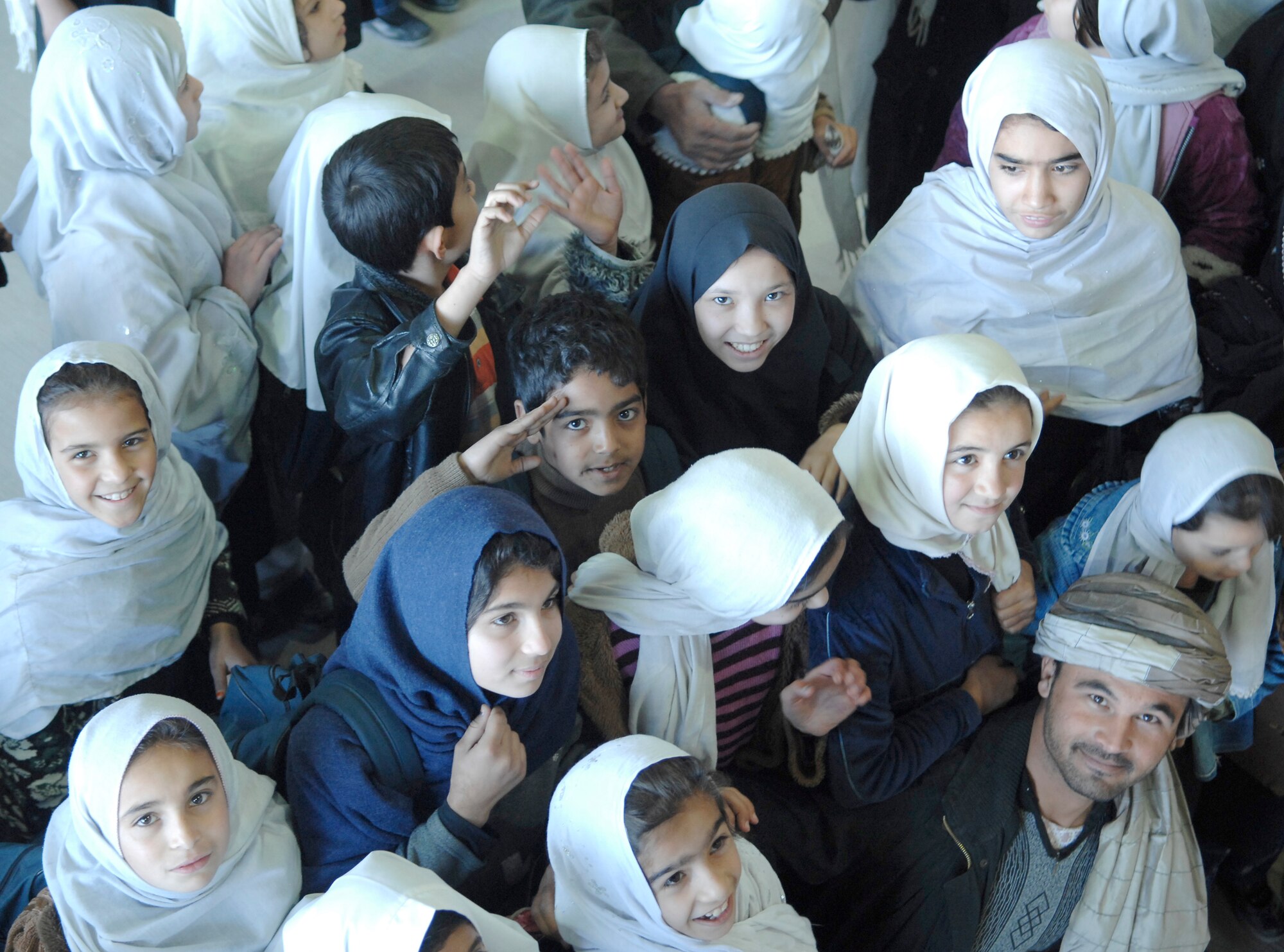 A young Afghan boy renders a salute while standing in a crowd of fellow students and a teacher Dec. 31, 2009, at Kandahar Airfield, Afghanistan. Students were able to see examples of the partnership between coalition forces and Afghan military members working together at the Afghan National Army Air Corps hangar. (U.S. Air Force photo/Staff Sgt. Angelique N. Smythe)