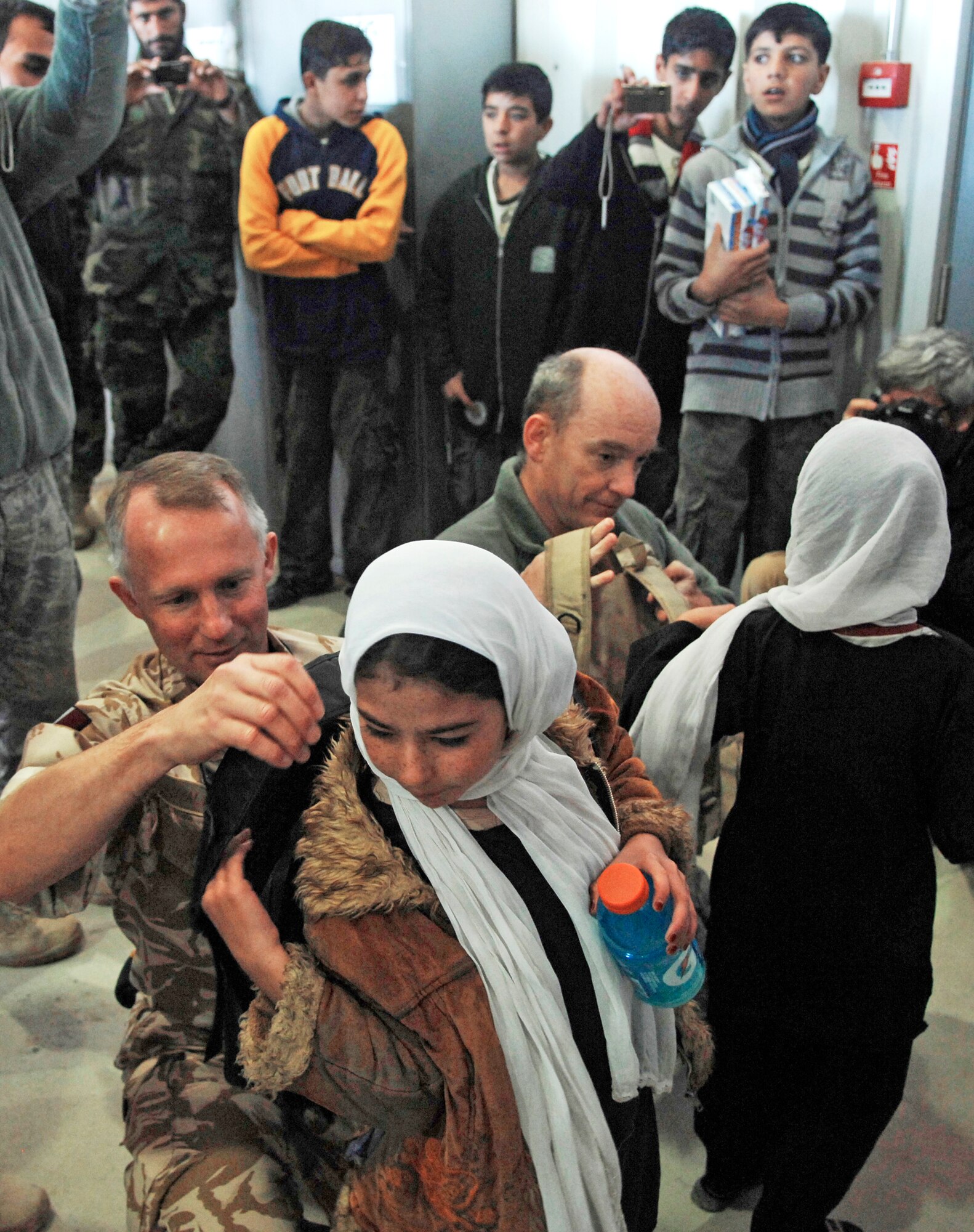 Royal Air Force Air Commodore Malcolm Brecht assists a young girl with putting on a backpack filled with school supplies Dec. 31, 2009, during her visit to Kandahar Airfield, Afghanistan. Air Commodore Brecht is the commander of Kandahar Airfield. (U.S. Air Force photo/Staff Sgt. Angelique N. Smythe)