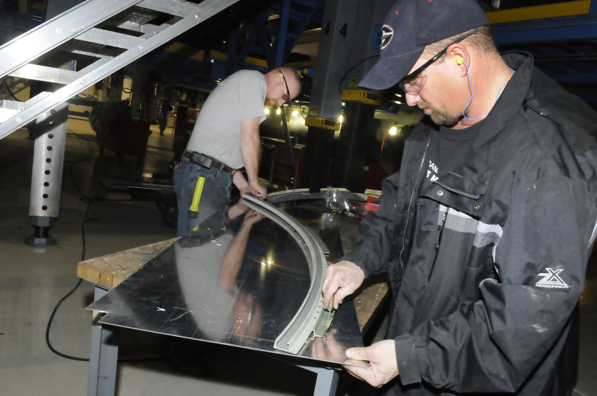 L-R, Steven Smith and David Kennell work on a paratroop door track for the C-130 undergoing HVM Dec. 17. U.S. Air Force photo by Sue Sapp