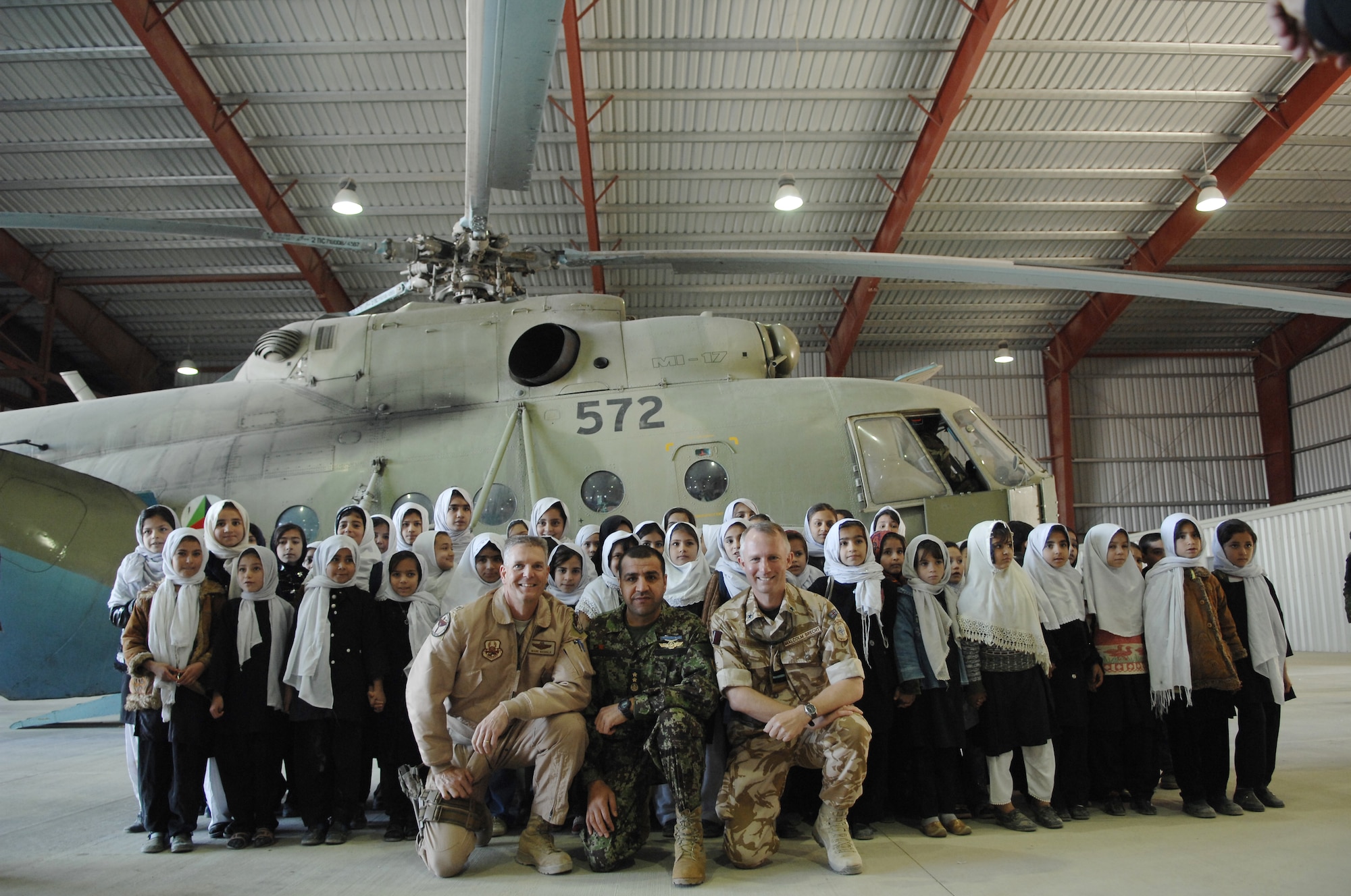 Col. Mark Nichols, 438th Air Expeditionary Training Group commander, Maj. Gen. Abduhl Raziq Sherzai, commander of the ANAAC, and Air Commodore Malcolm Brecht, commander of Kandahar Airfield, take photos with Afghan students in the Afghanistan National Army Air Corps hangar on Kandahar Airfield. Approximately 250 children from local schools in Kandahar City visited the ANAAC Dec. 31, 2009. (U.S. Air Force photo by Staff Sgt. Angelique N. Smythe/Released)  