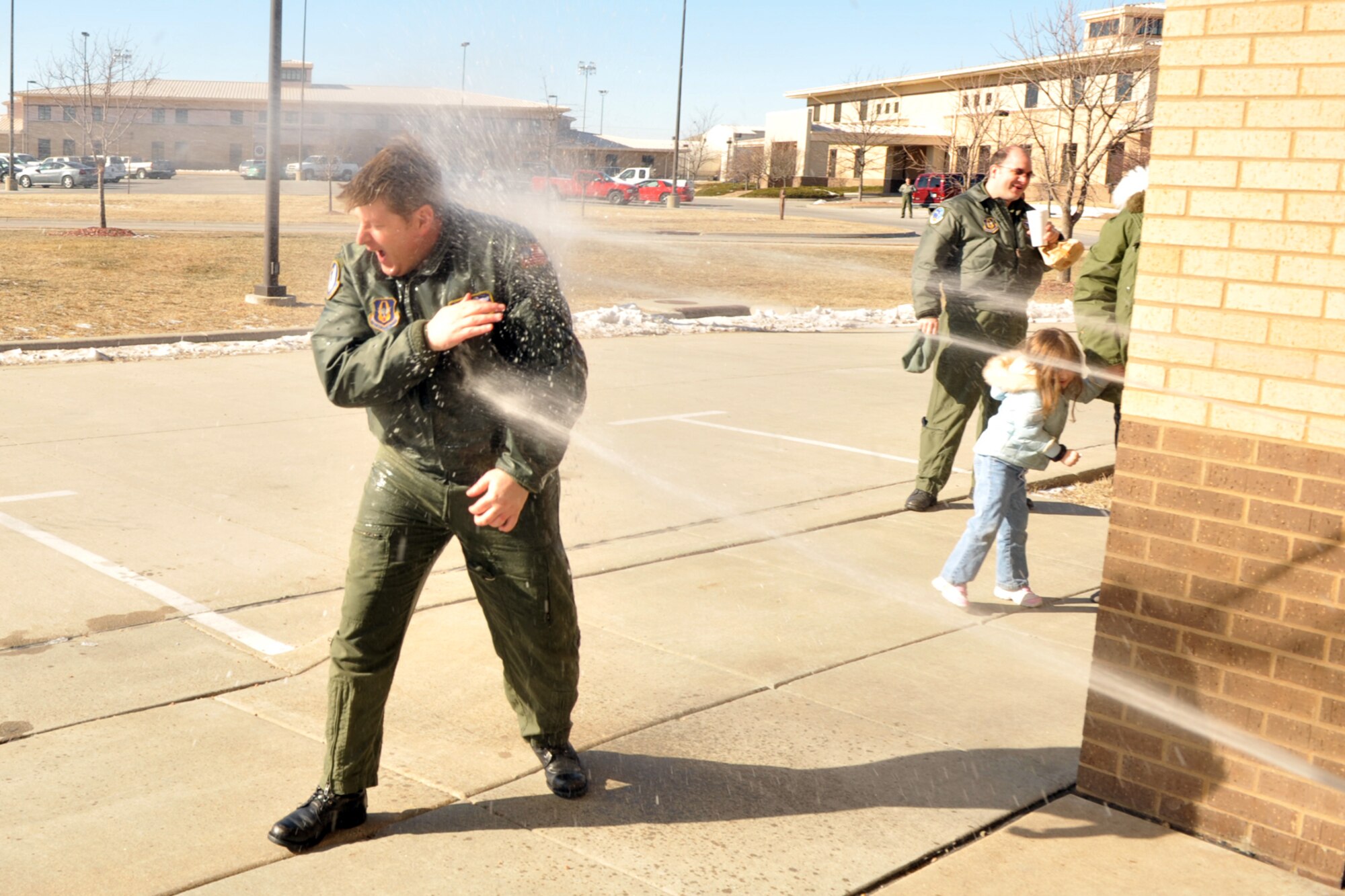 Tech. Sgt. Greg Carron is ambushed by three of his fellow Airmen armed with water sprayers at McConnell Air Force Base, Kan., Saturday. Sergeant Carron had just finished his final flight as a KC-135 boom operator before retiring from the Air Force Reserve. The wet-down, a final-flight tradition for flyers, was postponed until he was close to indoors because of bitter-cold temperatures at the base. (U.S. Air Force photo/Master Sgt. Jason Schaap)