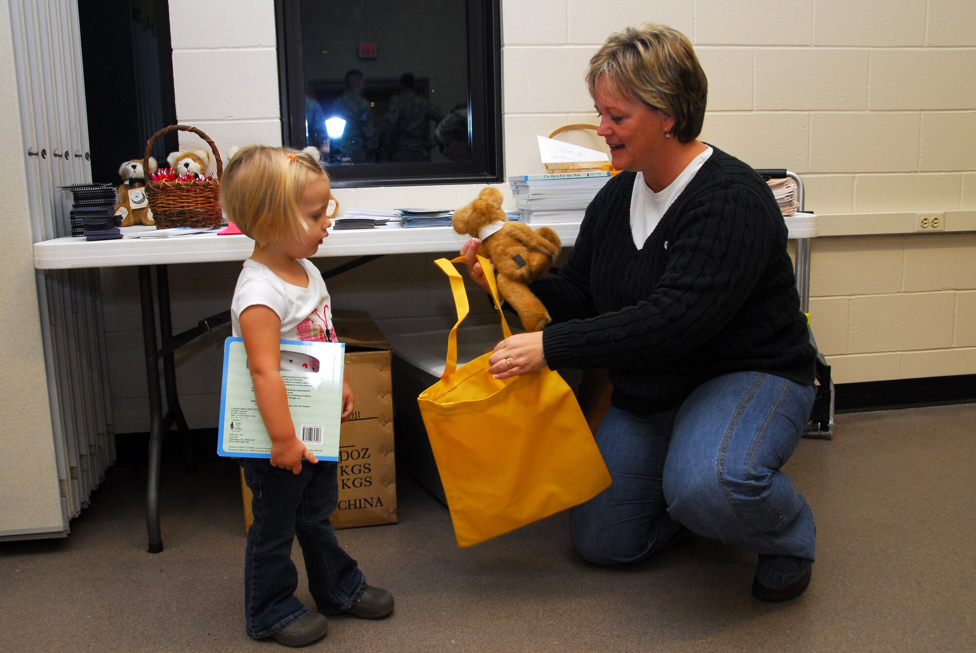 Wing Family Program Coordinator, Jennifer Kuhlman, of the 148th Fighter Wing gives a teddy bear to a daughter of a deploying Securtiy Forces member before a deployment Oct. 19th, 2009 at the Air National Guard Base in Duluth, Minn.  (U.S. Air Force photo by Master Sgt. Jason Rolfe)