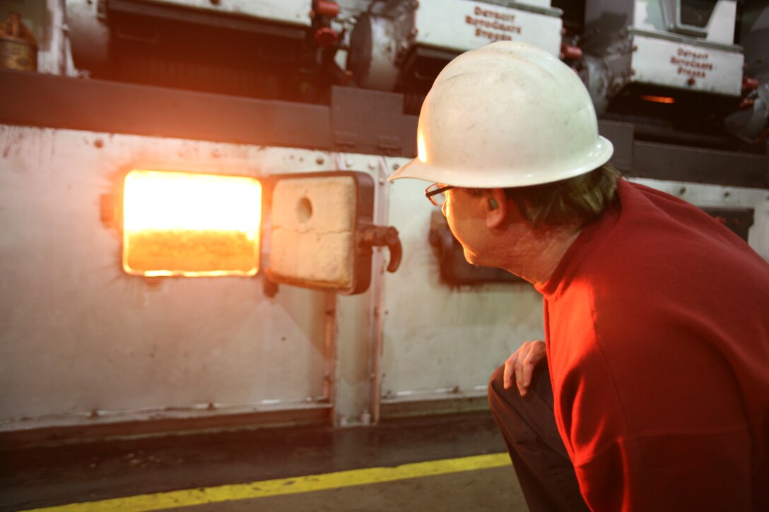 Boiler plant operator Richard B. Blankenship observes coal burning in one of the furnaces used to heat the boilers in the central heating plant. Careful regulation of a boiler’s temperature and internal pressure are crucial in maintaining safety and efficiency.