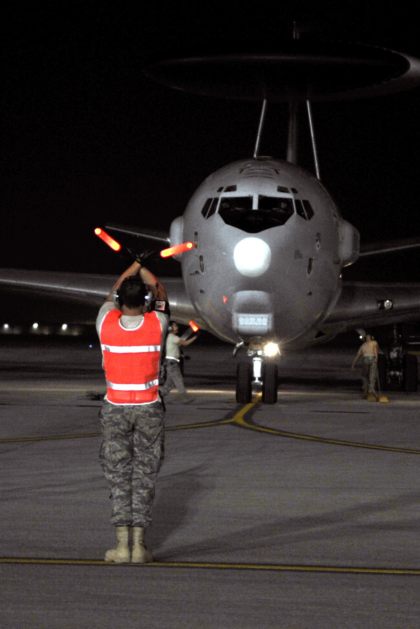 A maintenance Airman waves an E-3 Sentry Airborne Warning and Control System aircraft to come in to park on the flightline of a non-disclosed base in Southwest Asia on Jan. 10, 2010. The aircraft and Airmen, assigned to the 380th Air Expeditionary Wing, support Operations Iraqi Freedom and Enduring Freedom and the Combined Joint Task Force-Horn of Africa. (U.S. Air Force Photo/Tech. Sgt. Scott T. Sturkol/Released)