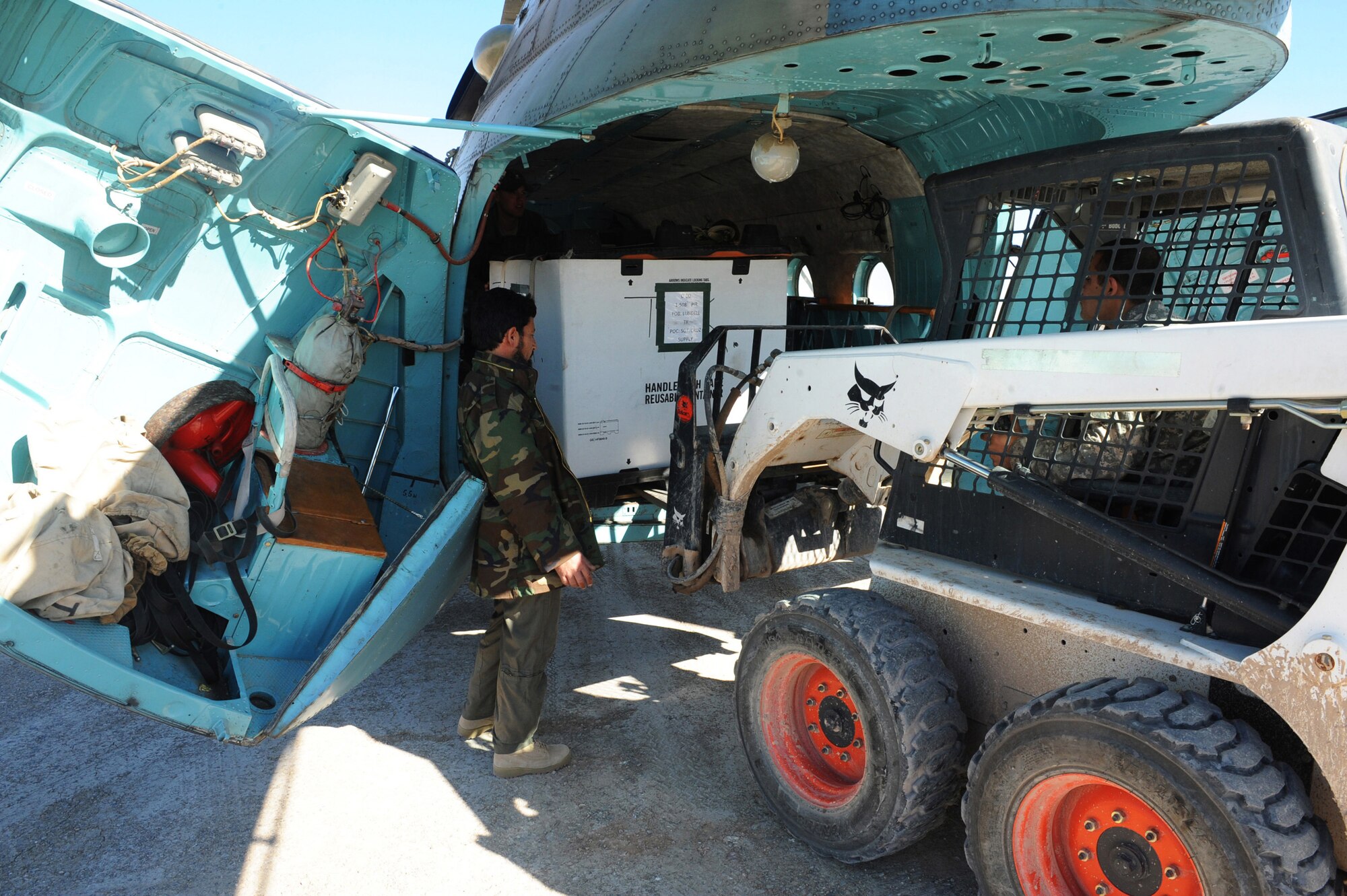 An Afghanistan National Army Air Corps flight engineer helps a U.S. Soldier unload a pallet of cargo out of an Mi-17 cargo door during a joint mission Jan. 7, 2010, at Forward Operating Base Tarin Kowt, Afghanistan. Missions like this are becoming more common as 441st Air Expeditionary Advisory Squadron Airmen mentor Mi-17 helicopter pilots.(U.S. Air Force photo/Staff Sgt. Manuel J. Martinez)
