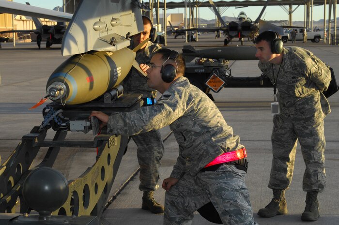 NELLIS AIR FORCE BASE, Nev.-- Staff Sgt. Shiloh Blanco, a weapons loader, 57th Aircraft Maintenance Squadron, adjusts the table of the MJ-1 bomb lift truck as  Senior Airman Zebulon Pritchard, also with the 57AMXS, stabilizes  the MK-82LD while Staff Sgt. Mark Krok, Weapons Standardization, evaluates during the load crew competition here Jan. 8.  The quarterly weapons load crew competition tests the skills of airman on six different teams. The Airmen are judged on speed, accuracy and safety. (U.S Air Force photo by Staff Sgt. Taylor Worley)(Released)
