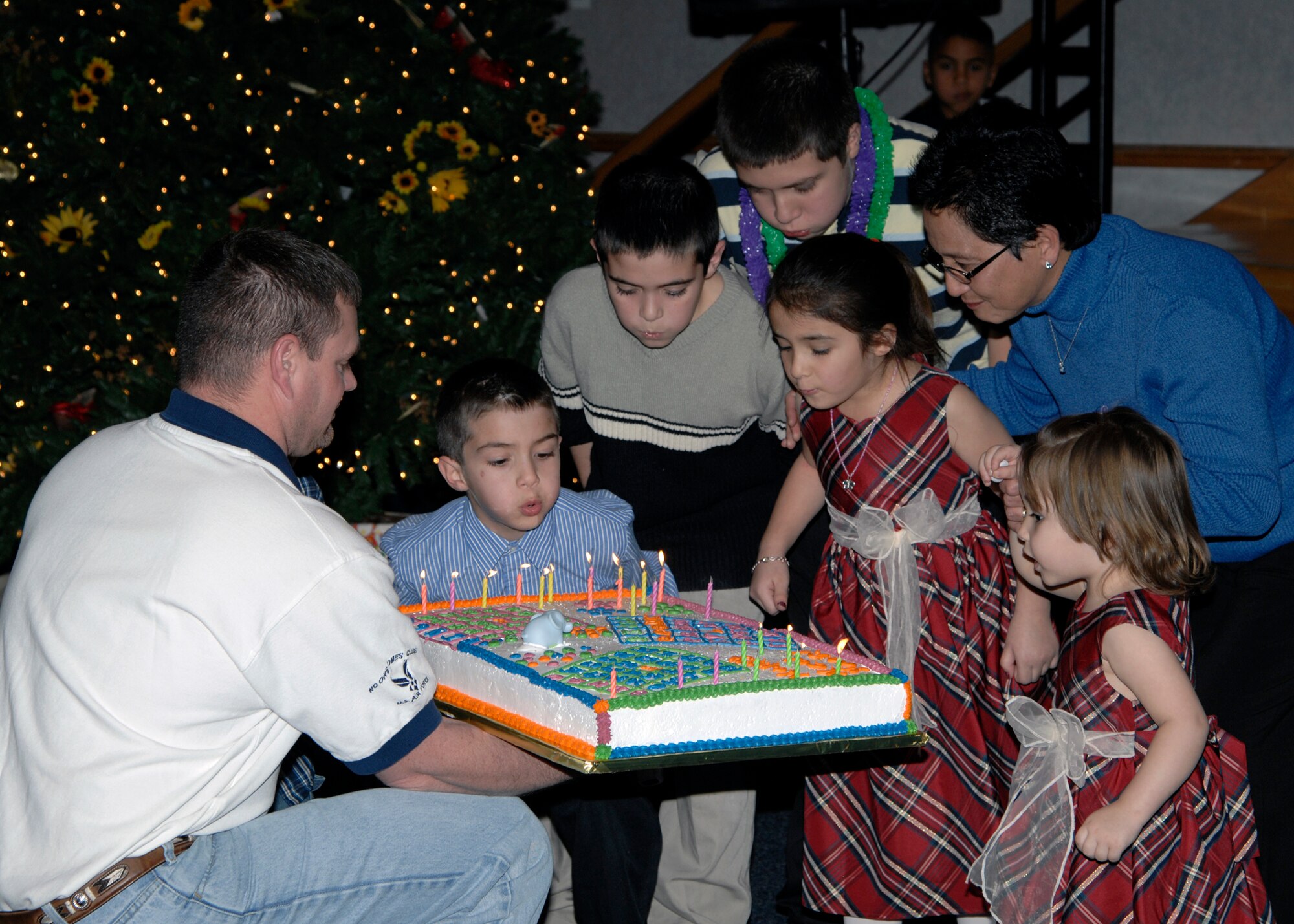 Sandy Jacobs, Team McConnell family member, and her grandchildren blow out candles on her birthday cake, held by Tech. Sgt. Carl Swartz, 22nd Force Support Squadron, during the New Year’s Eve party, Dec. 31, 2009, at McConnell Air Force Base, Kan. Mrs. Jacobs celebrated her 58th birthday at the party with her family. Party activities included bingo and children singing karaoke. (U.S. Air Force/Airman 1st Class Justin Shelton)