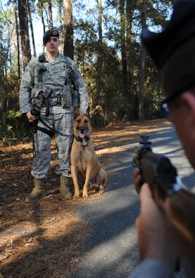 MOODY AIR FORCE BASE, Ga. -- Senior Airman Ryan Federick, 23rd Security Forces Squadron military working dog handler, and his MWD, Rico, stand ready as Tech. Sgt. Randy Dauzat, 23rd Security Forces Squadron military working dog section NCO in-charge, demonstrates the AK-47 simulator here Dec. 22. The simulator is used to train MWDs to become accustom to the sound of a real world AK-47 assault rifle being fired. (U.S. Air Force photo by Airman 1st Benjamin Wiseman)