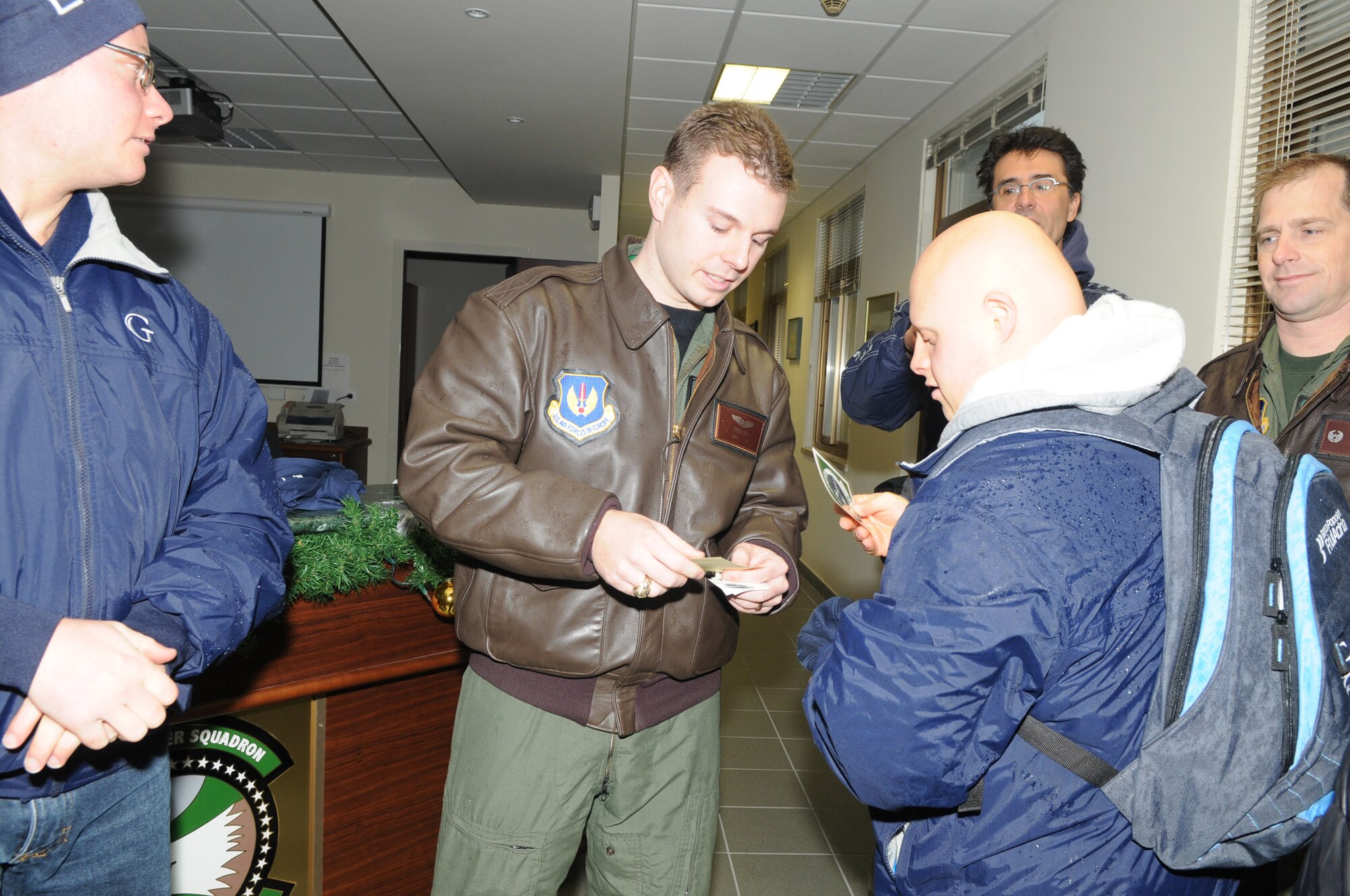 Capt. Tyler B. Smith, 555 Fighter Squadron fighter pilot, hands out patches and stickers from the 555 FS after they completed their visit here Jan 9. The team, which trains twice a week at the Aviano swimming pool, consists of swimmers with intellectual disabilities. They are part of the Special Olympics program, which is the world's biggest sports organization for people with disabilities. (U.S. Air Force photo/Staff Sgt. Mercedes Crossland)