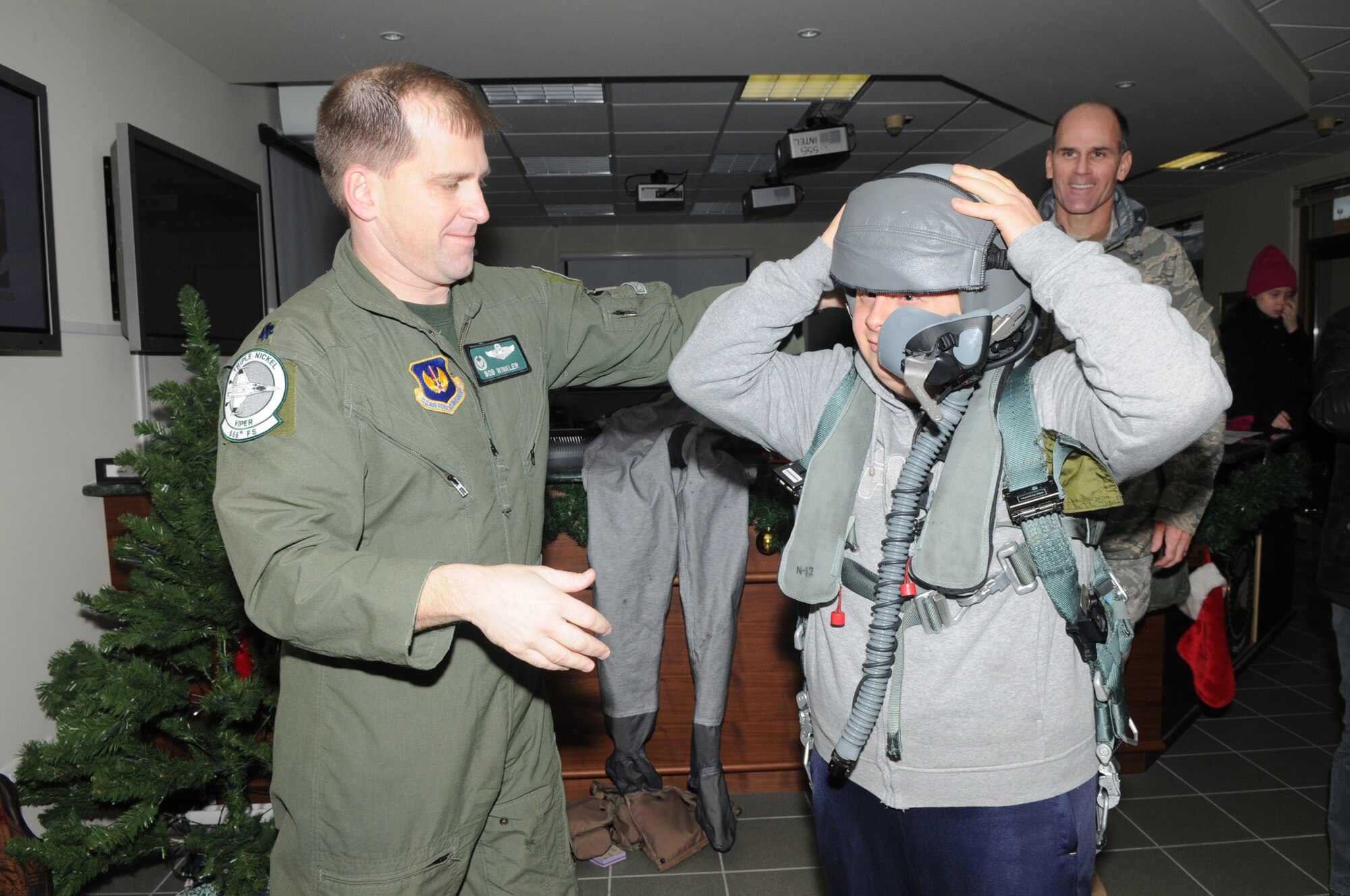 Lt. Col. Robert P. Winkler, 555 Fighter Squadron commander, shows off flight equipment to members of the Gymnasium Special Swim team during a visit here Jan. 9. The team, which trains twice a week at the Aviano swimming pool, consists of swimmers with intellectual disabilities. They are part of the Special Olympics program, which is the world's biggest sports organization for people with disabilities. (U.S. Air Force photo/Staff Sgt. Mercedes Crossland)