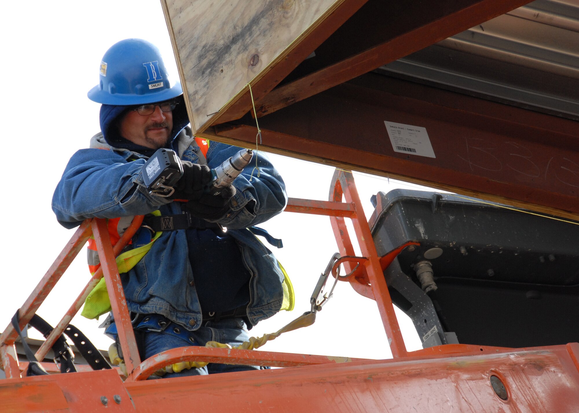 A construction worker, on a raised lift, uses a drill on the right side of the Joint Strike Fighter Training Facility construction site Jan. 8.  The temperatures and wind chill halted some of the construction activities Jan. 8, but work still continued.  Drills, saws, raised lifts and heavy movers could be heard all around the site.  (U.S. Air Force photo/Samuel King Jr.)