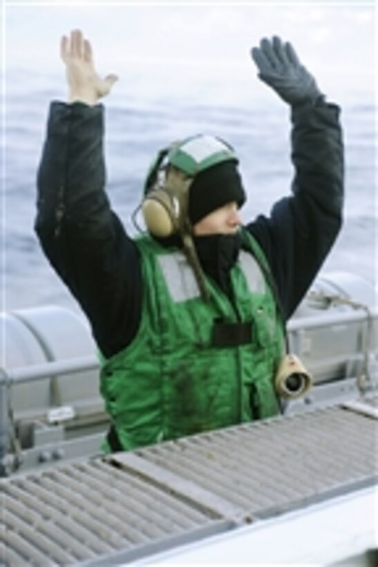 U.S. Navy Petty Officer 2nd Class Phillip Jukkola signals "hands clear" during safety preparations for flight operations aboard the aircraft carrier USS Dwight D. Eisenhower (CVN 69) in the Atlantic Ocean on Jan. 3, 2010.  The Eisenhower is on a six-month deployment as a part of the ongoing rotation of forward-deployed forces.  
