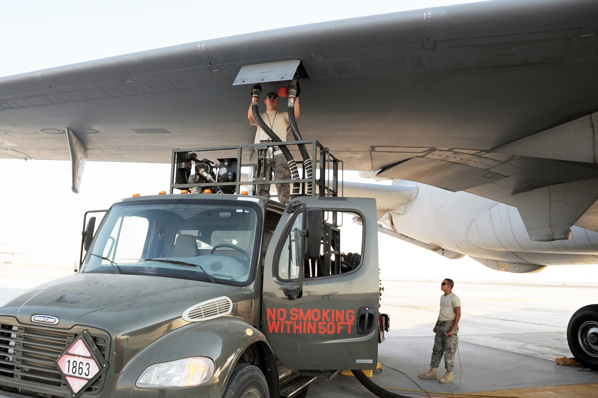 Airman 1st Class Dustin Hathcock and Airman Jose Goitia work together to refuel a KC-10 Extender during flightline operations at base in Southwest Asia Jan. 6, 2010. Airman Hathcock is a KC-10 crew chief and Airman Goitia is a 380th Expeditionary Logistics Readiness Squadron fuel management flight fuels distribution apprentice. (U.S. Air Force photo/Tech. Sgt. Scott T. Sturkol)