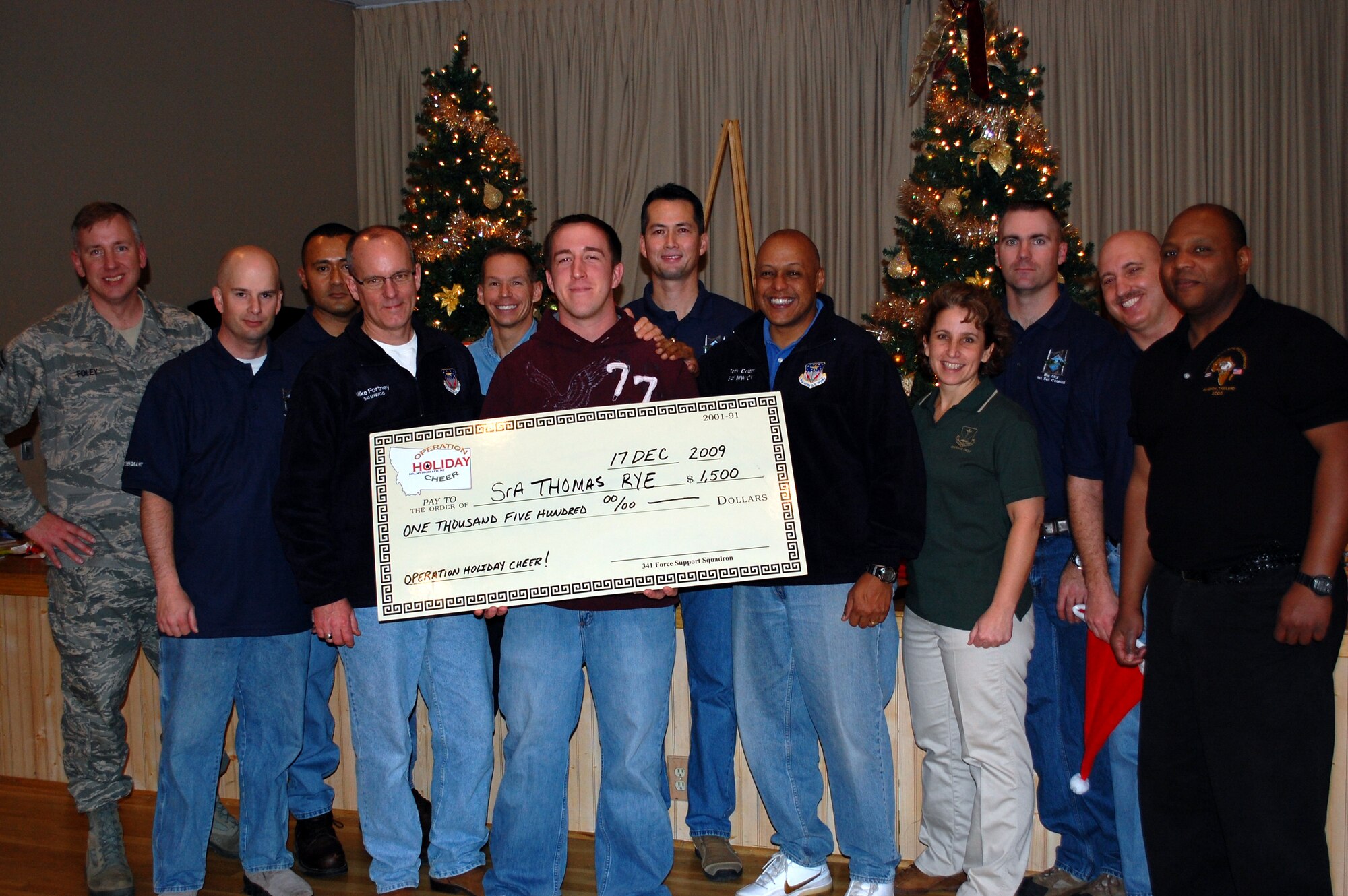 MALMSTROM AIR FORCE BASE, Mont. -- Senior Airman Thomas Rye, center, poses with a check that will pay for his two round-trip airline tickets to anywhere in the Continental United States that he won during the Operation Holiday Cheer wrap-up party Dec. 18, 2009. Also pictured are the squadron first sergeants and 341st Missile Wing leadership, Col. Michael Fortney, commander; Col. Anthony Cotton, vice commander; and Chief Master Sgt. Cari Kent, command chief. (U.S. Air Force photo/2nd Lt. Marshell Slater)