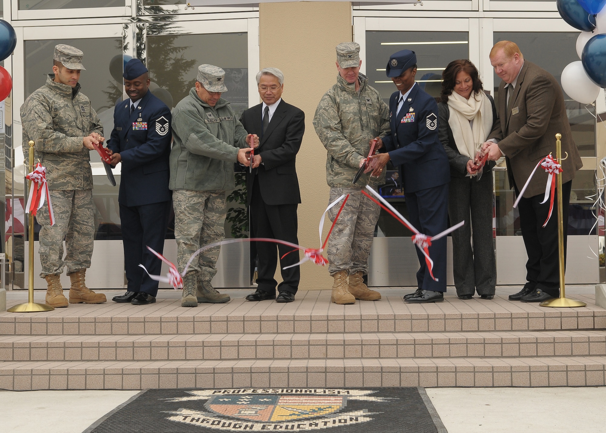 YOKOTA AIR BASE, Japan -- (from left to right) Chief Master Sgt. Benjamin Caro, 374th Airlift Wing command chief, Master Sgt Thaddeus Brannon, Airman Leadership School career assistance advisor, Col. Rafael Quezada, 374th Mission Support Group commander, Yasuya Nakazono, Director of Procurement Division and North Kanto Defense Bureau, Col. Mark Hicks 374th Airlift Wing commander, Master Sgt. Nanette Klingaman, Airman Leadership School commandant, Catheren Gill, Chief of Engineering and construction, United States Army Core of Engineers, and Louis Van De Mark, director of the 374th Force Support Squadron cut a ribbon that represents the offcial opening of the new Professional Development Center Dec. 12. The new building offers bigger classrooms, more amenities, and a better location for students. (U.S. Air Force photo/Airman 1st Class Sean Martin) 