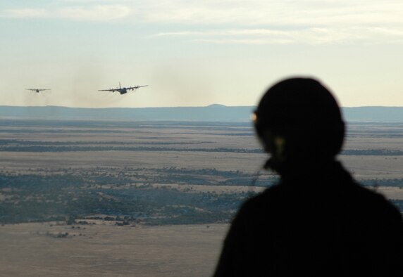 Tech. Sgt. Scott Gordon looks on as two C-130 Hercules transport aircraft fly in formation to a simulated drop zone Dec. 15 during a training mission over eastern Colorado. The training mission also served as a media flight for a reporter and photographer from the Colorado Springs, Colo. Gazette newspaper. Sergeant Gordon is a C-130 loadmaster assigned to the Air Force Reserve's 302nd Airlift Wing. The 302nd AW is based at Peterson Air Force Base in Colorado. (U.S. Air Force photo/Staff Sgt. Stephen J. Collier)